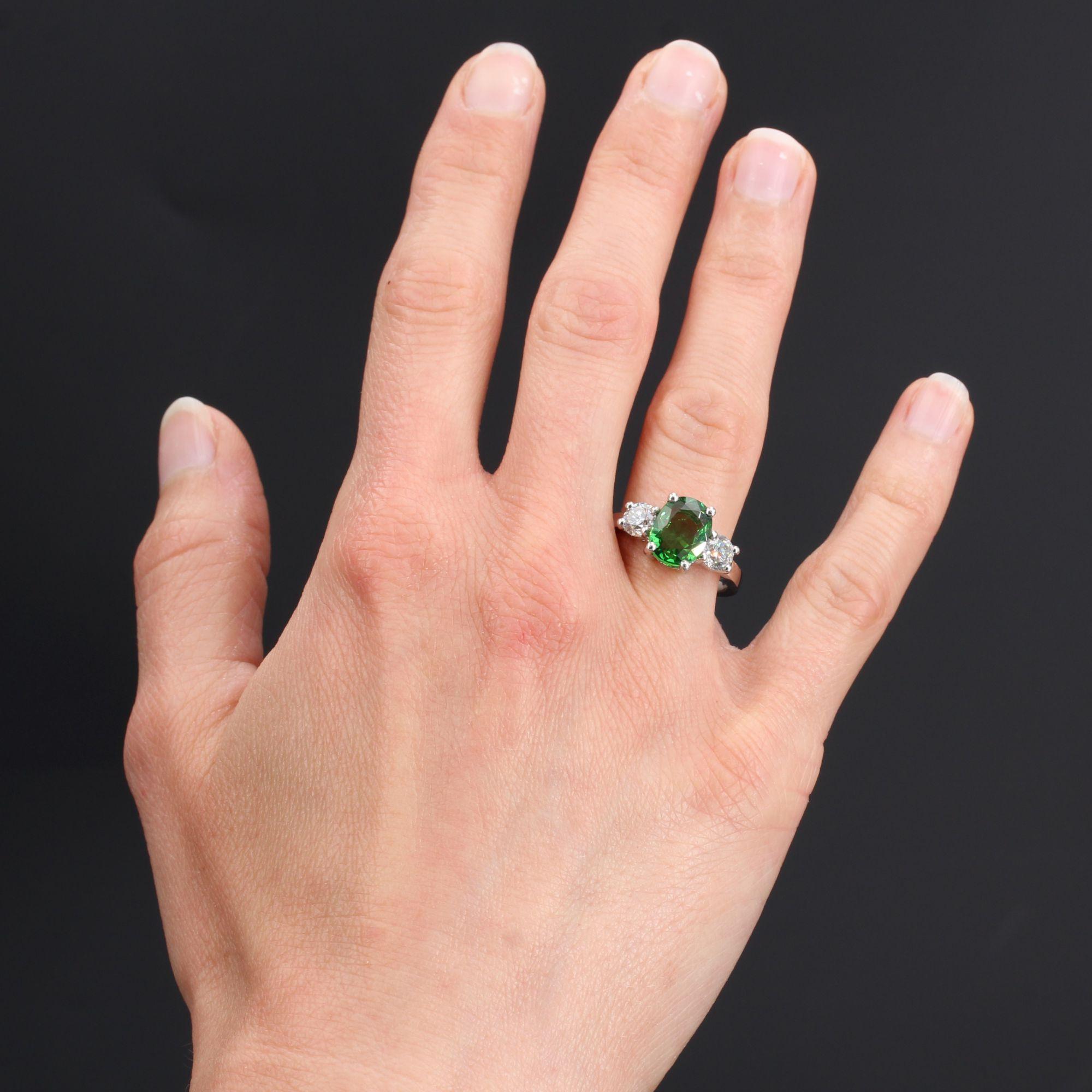 Ring in platinum, dog head hallmark.
This modern platinum ring is set with 4 claws on its top, with an oval tsavorite green garnet supported by 2 modern brilliant-cut diamonds each set with 4 claws.
Weight of the garnet : about 3.06 carats, total