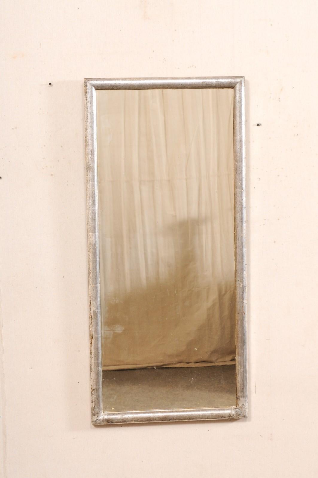 Specchio da parete rettangolare francese, con cornice in legno dipinto d'argento, risalente al XIX secolo. Questo specchio antico proveniente dalla Francia presenta un design dal profilo molto semplice e pulito, con il vetro centrale incastonato in