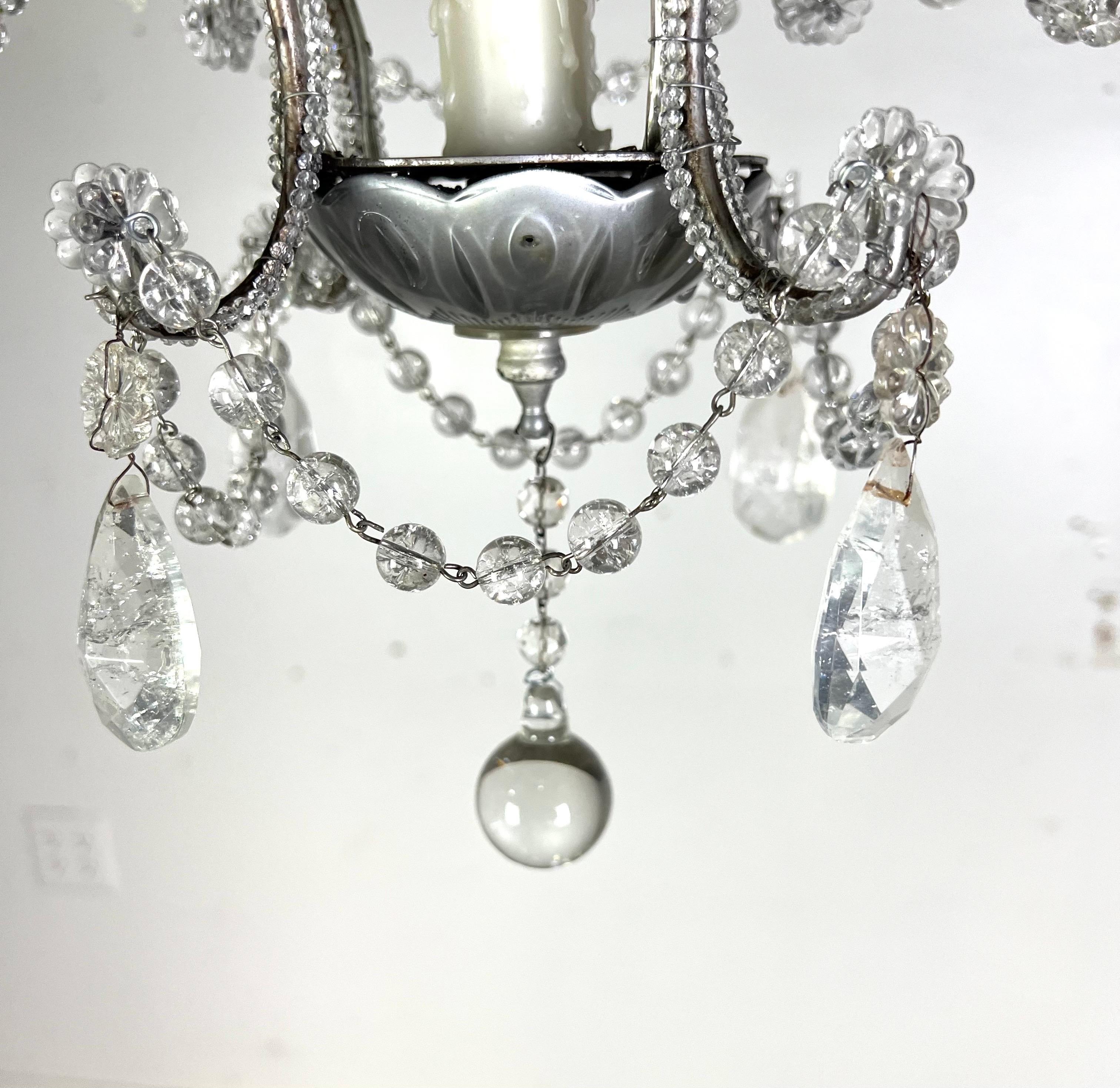 Lustre français (4) en cristal de roche avec guirlandes.  Ce lustre est de conception classique avec quatre bras, chacun contenant une ampoule en forme de bougie, et est orné d'ornements en cristal et de guirlandes de perles suspendues. Le lustre a