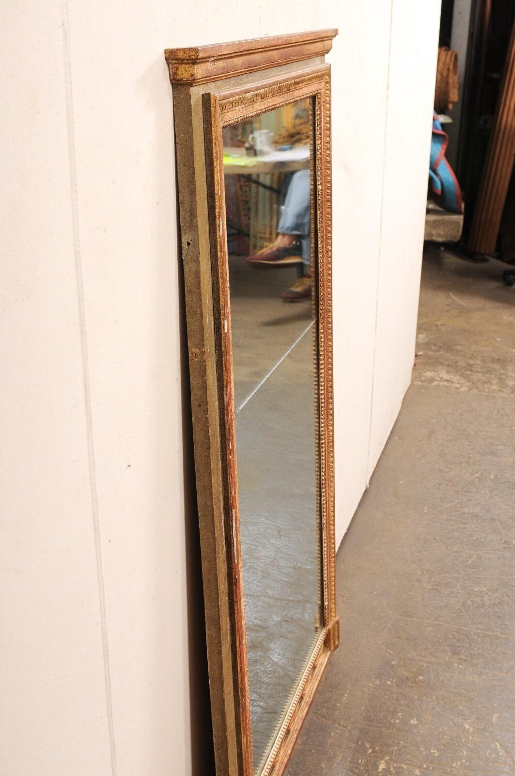 A French carved and painted wood wall mirror, with its original glass, from the 19th century. This antique mirror from France has a rectangular-shaped wood frame with clean lines about the outer perimeter, a molded top rail, and a series of carved