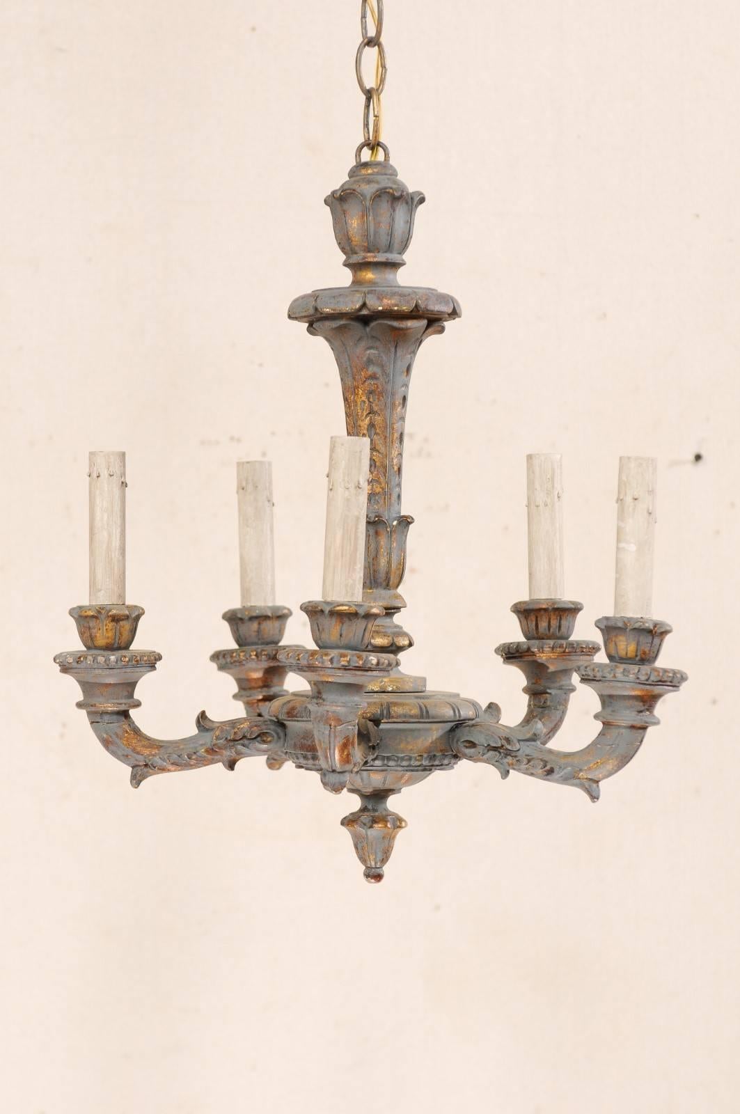 A cute French five-light painted and carved wood chandelier with scroll arms and wood bobèches. This French mid-20th century chandelier features a central wood column, with carved foliage motif, terminating into a carved bottom final. The carved