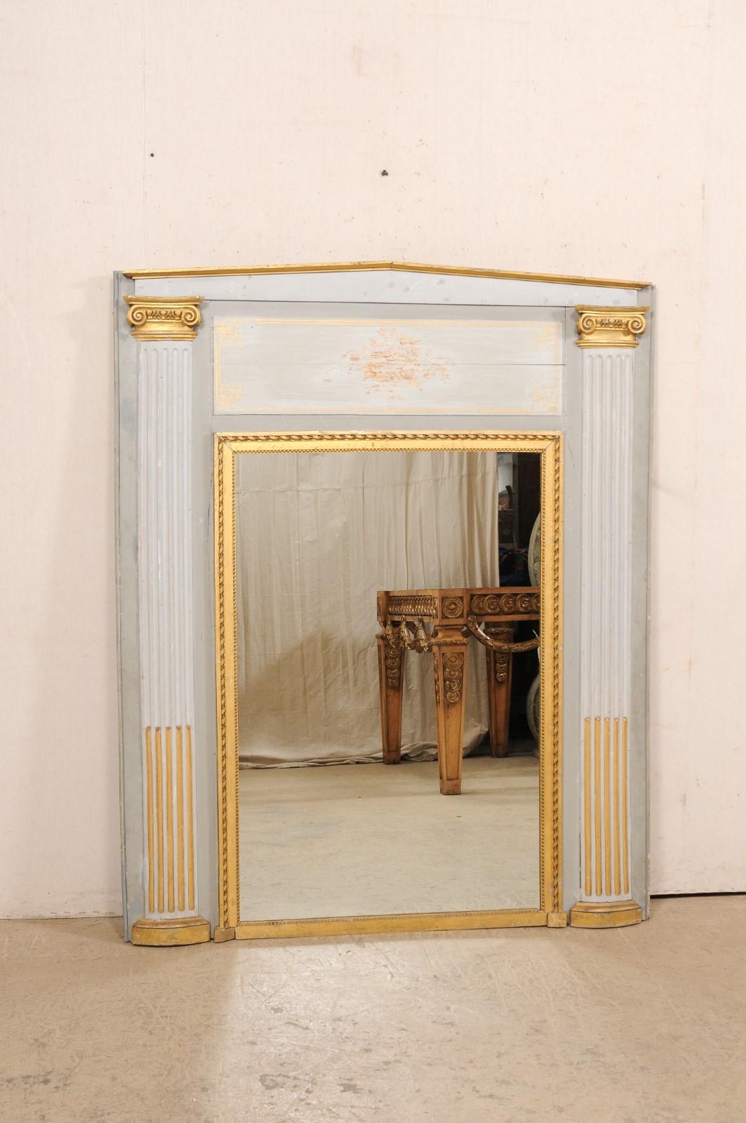 A large French over-mantle mirror with architectural accents from the 19th century. This antique mirror from France has a rectangular-shaped mirror at center with an inner gilt frame in ribbon and petite bead trim. The larger, outer surround