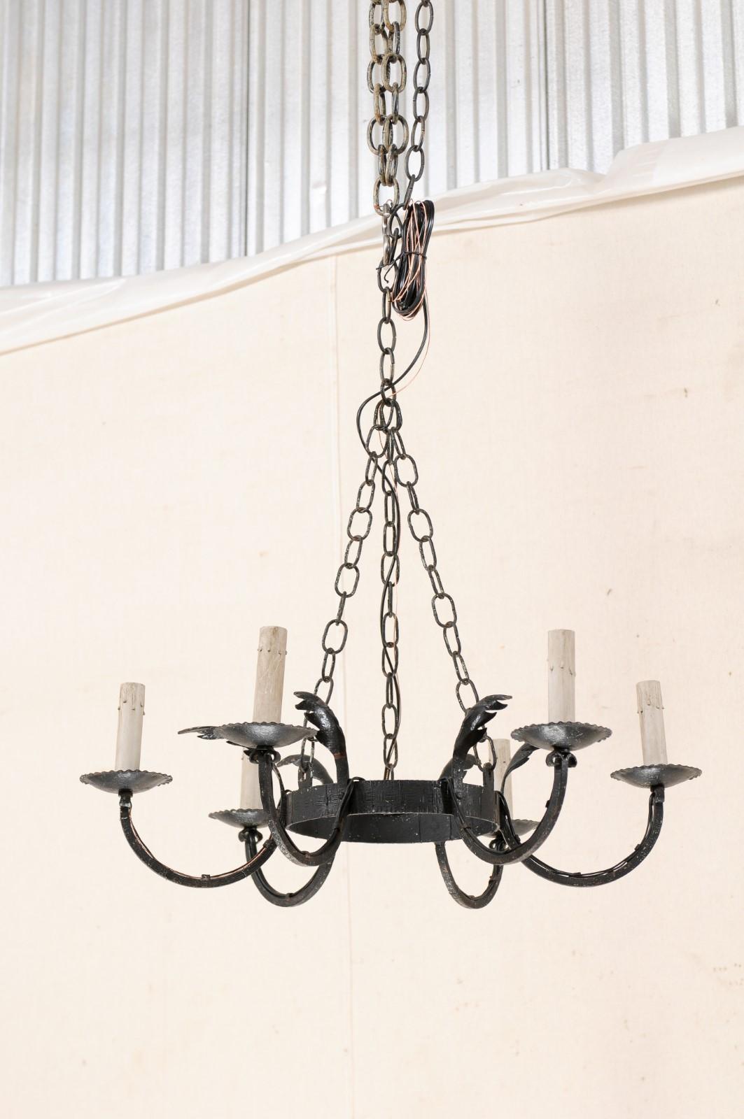 A French six-light circular-shaped iron chandelier from the mid-20th century. This vintage black iron chandelier from France features a central ring from which six c-scrolled arms are positioned reaching outwardly about it's perimeter, each adorn in