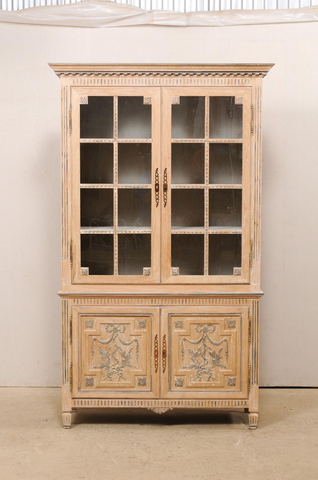A French tall cabinet from the mid 20th century. This vintage cabinet from France, which stands approximately 7.25 ft tall, has been designed with a Neoclassical influence, which is apparent in the nice dentil molding found beneath the upper