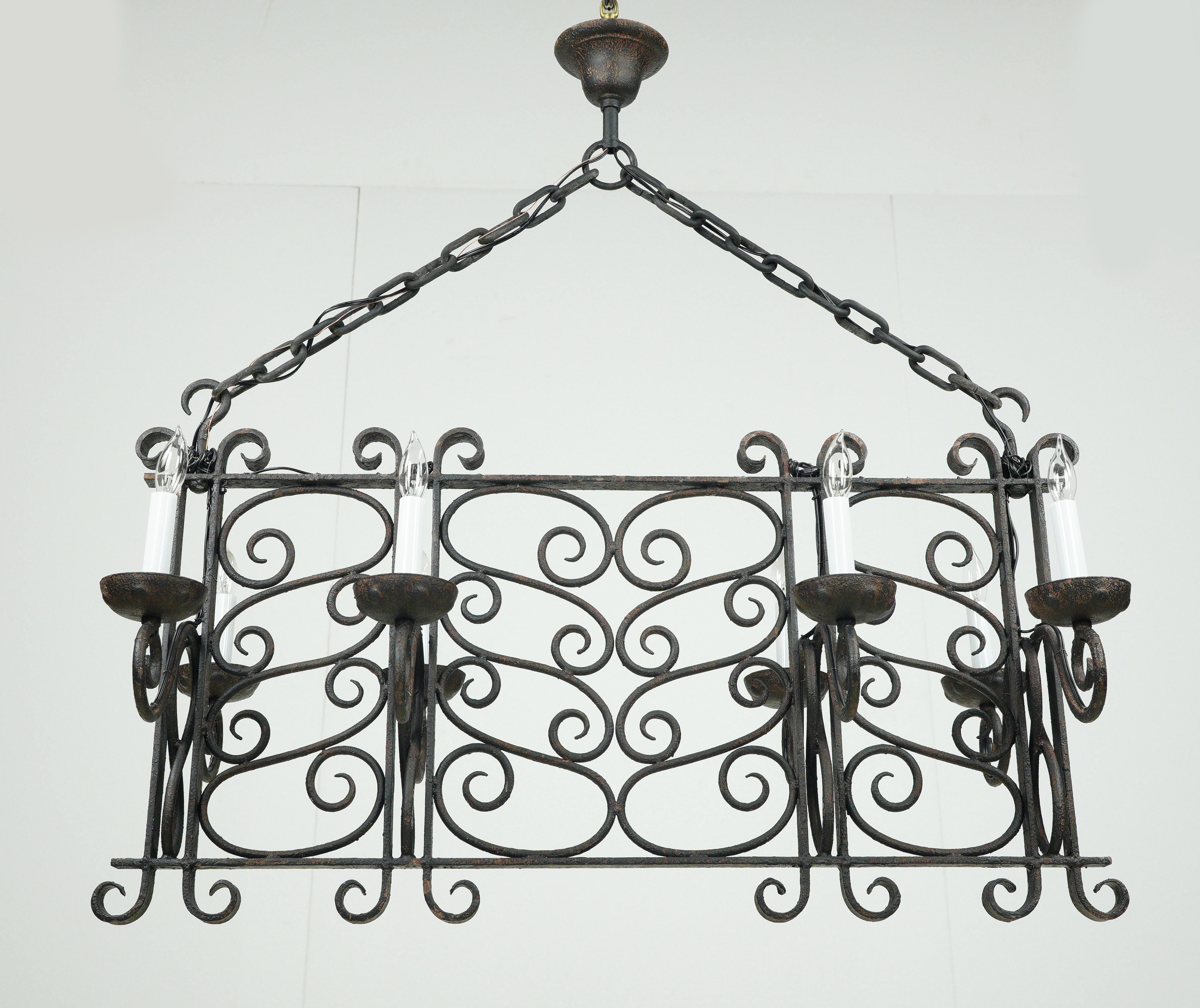 Lampadario in stile antico francese a forma di rettangolo realizzato in ferro battuto con finitura nera. È in buone condizioni, con un po' di ruggine superficiale. Questa lampada richiede otto lampadine a candelabro. Questa luce è cablata e pronta