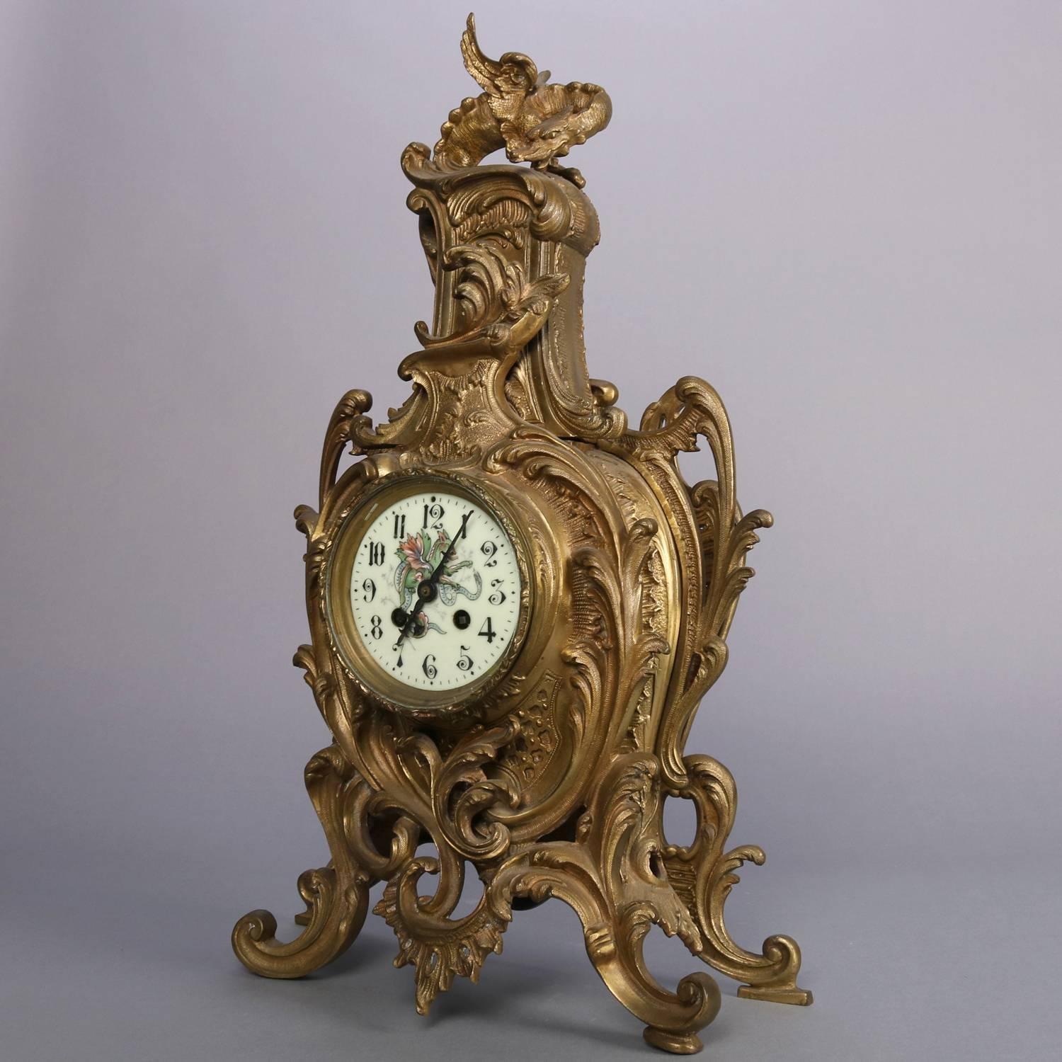 Antique French A D Mougin of Paris France, Rococo style mantel clock features pierced bronze case with scrolled acanthus overall and mythical winged dragon finial, porcelain face with hand painted winged dragon in victory over serpent, works stamped