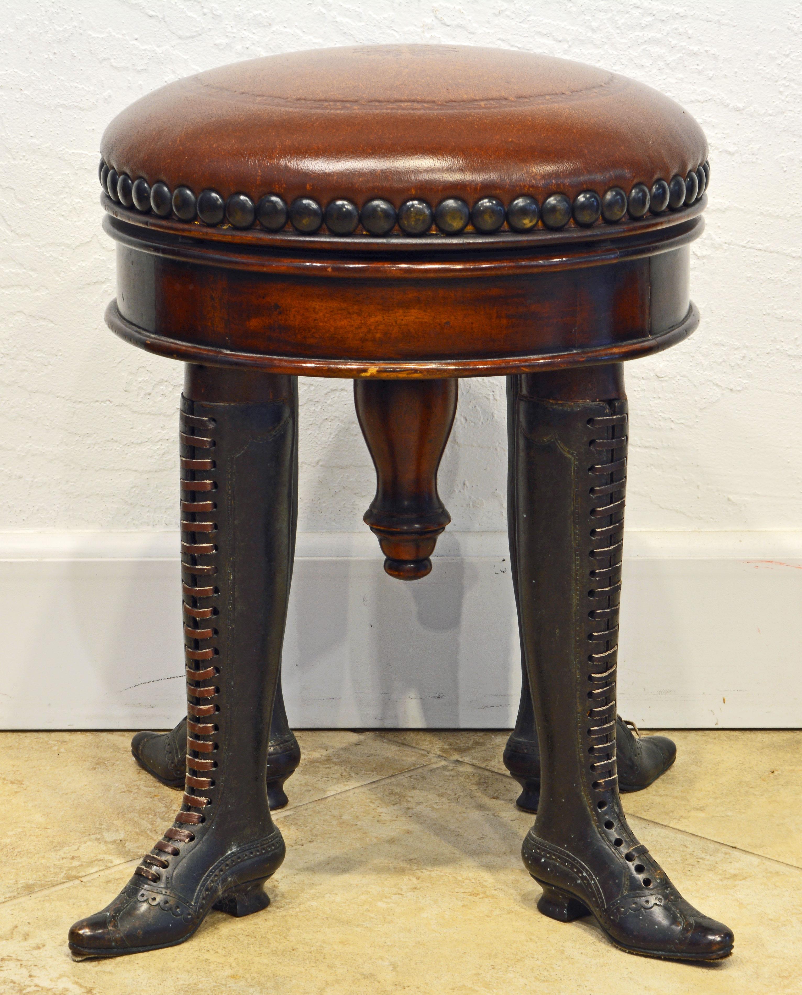 This very unusual piano stool or bench combines a height adjustable upholstered leather seat with mahogany frame and four bronze legs created in the shape of ladies boots mounted with leather laces. The bronze work is finely detalied simulating real