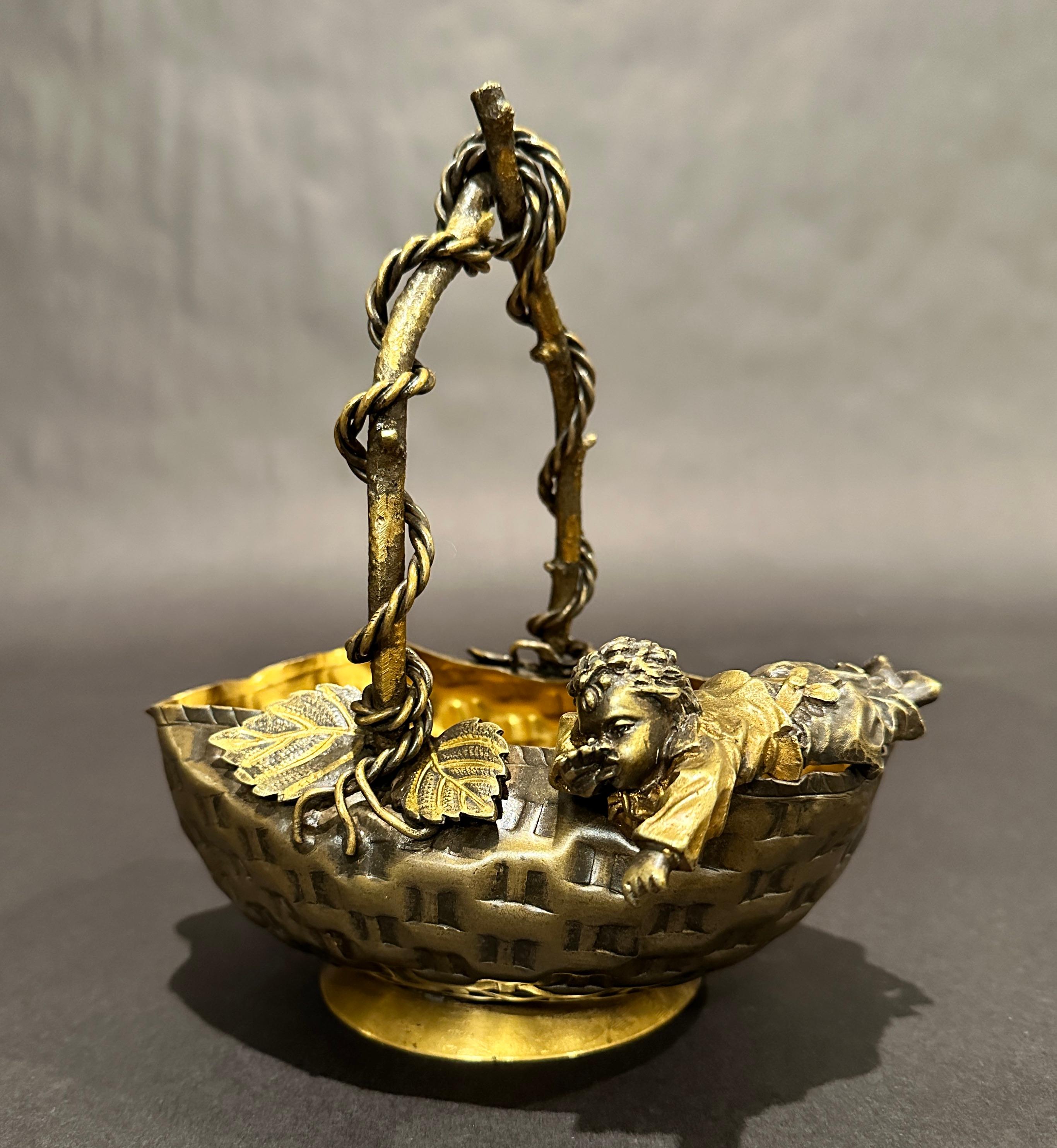 French aesthetic movement patinated and gilt bronze figural center bowl/basket, third quarter 19th century, formed as a large stylized woven basket. With leaves and vines as well as handle mounted with leavesand twisted vines. The edge of basket