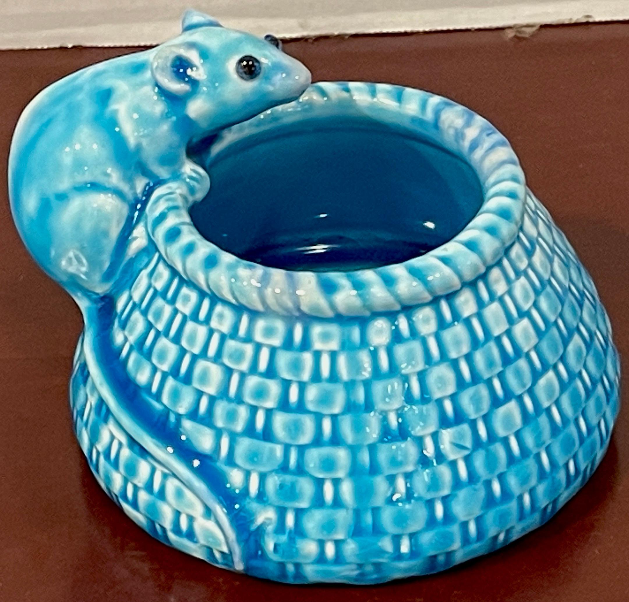 Vase en forme de souris figurée à glaçure turquoise d'esthétique française, un petit exemple fantaisiste avec une souris aux yeux émaillés et à la longue queue, reposant sur le bord d'un panier. Nombreuses lettres et chiffres imprimés.
  