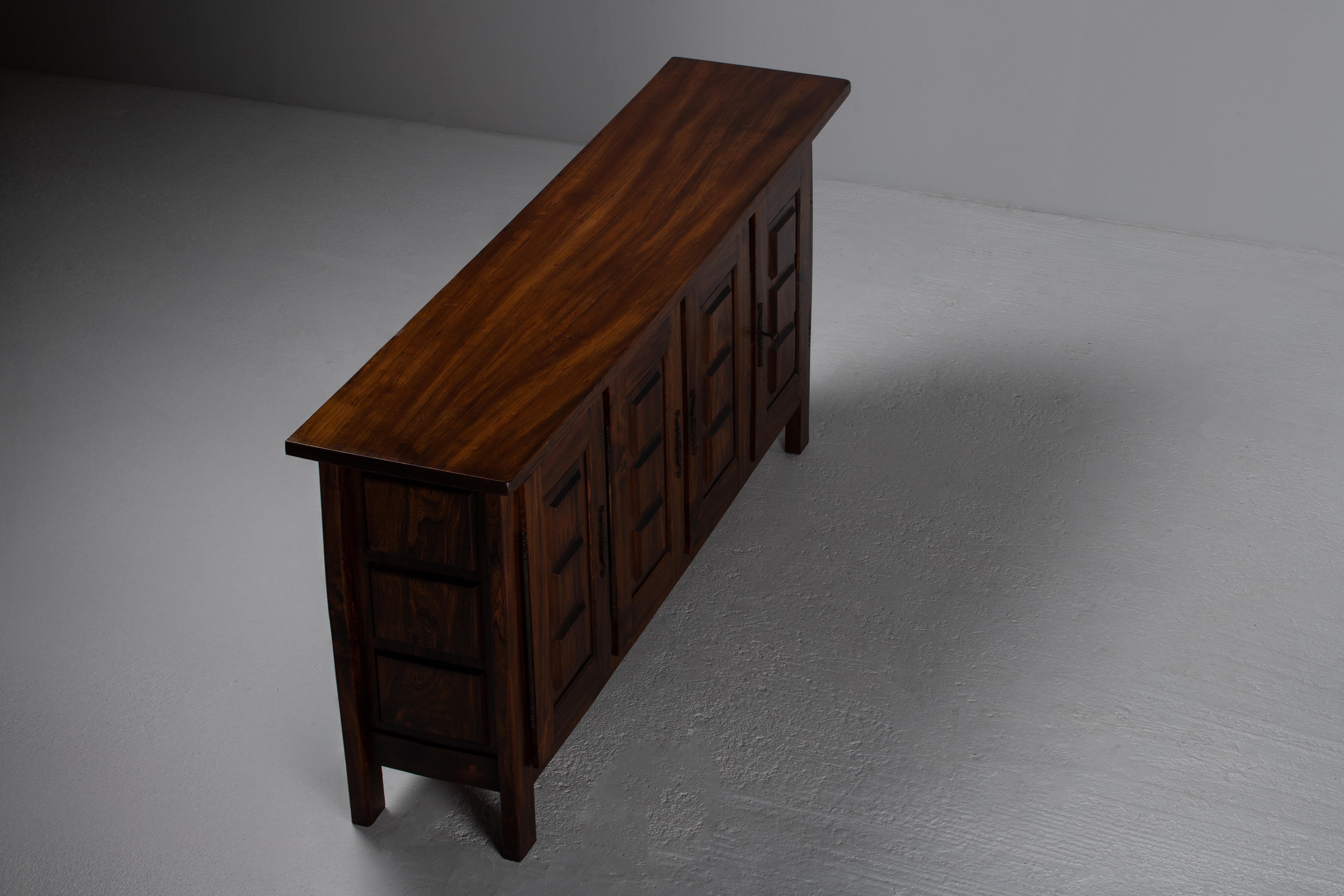 Questo buffet alpino francese degli anni '50, realizzato in legno massiccio di Oak, incarna l'estetica scultorea e funzionale sperimentata da Guillerme et Chambron e Charlotte Perriand. I suoi audaci pannelli geometrici in rilievo creano un gioco
