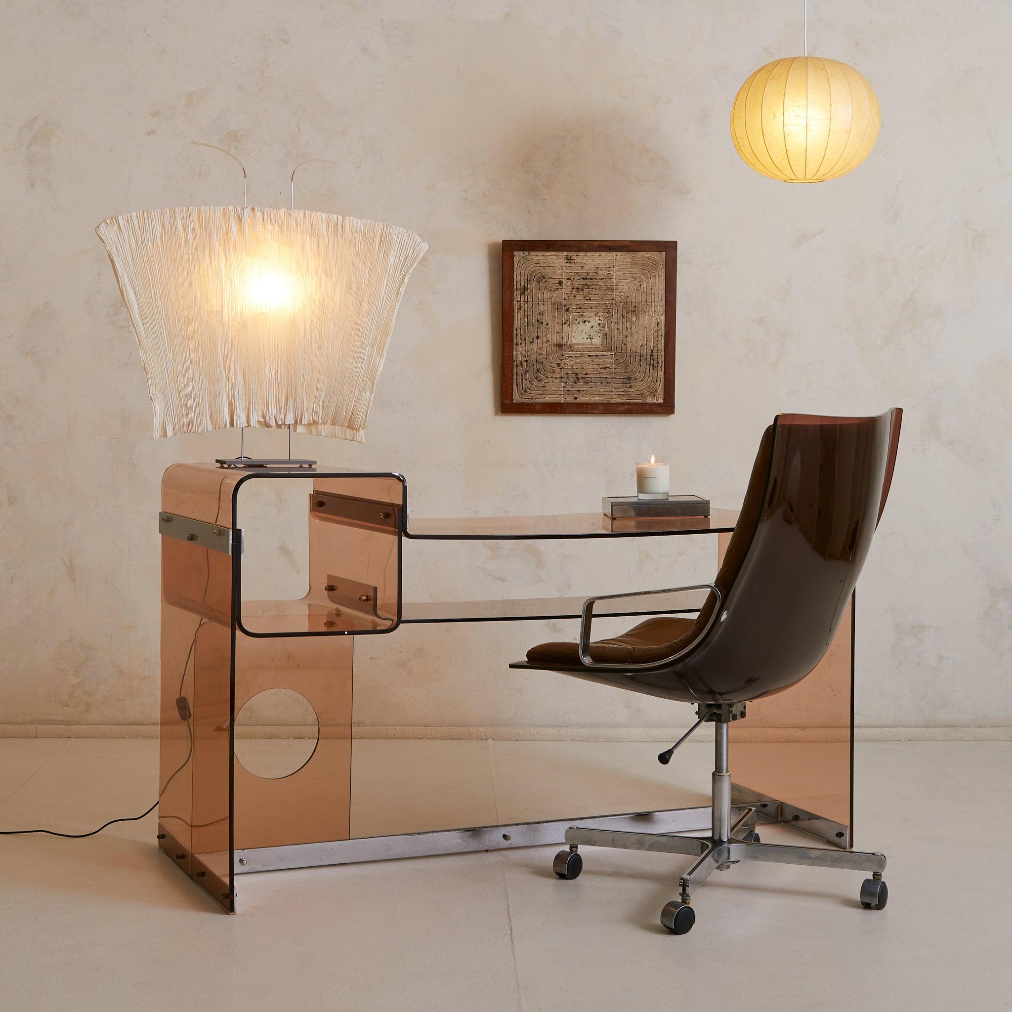 Rare and sculptural, this 1970s French desk merges amber-smoked plexiglass with polished chrome in a futuristic silhouette. Attributed to Michel Dumas, it features fluid, curved lines and a distinctive circular cutout that punctuates the side panel.