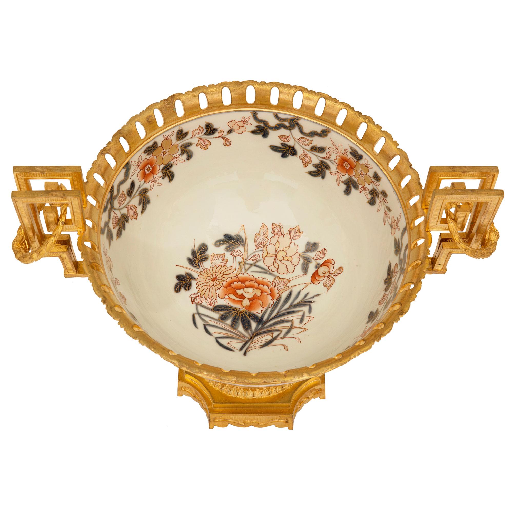 An elegant French and Asian collaboration 19th century Louis XVI st. ormolu and Imari porcelain centerpiece bowl. The centerpiece is raised by a beautiful square ormolu base with concave corners and decorated with lovely recessed fluted designs. The