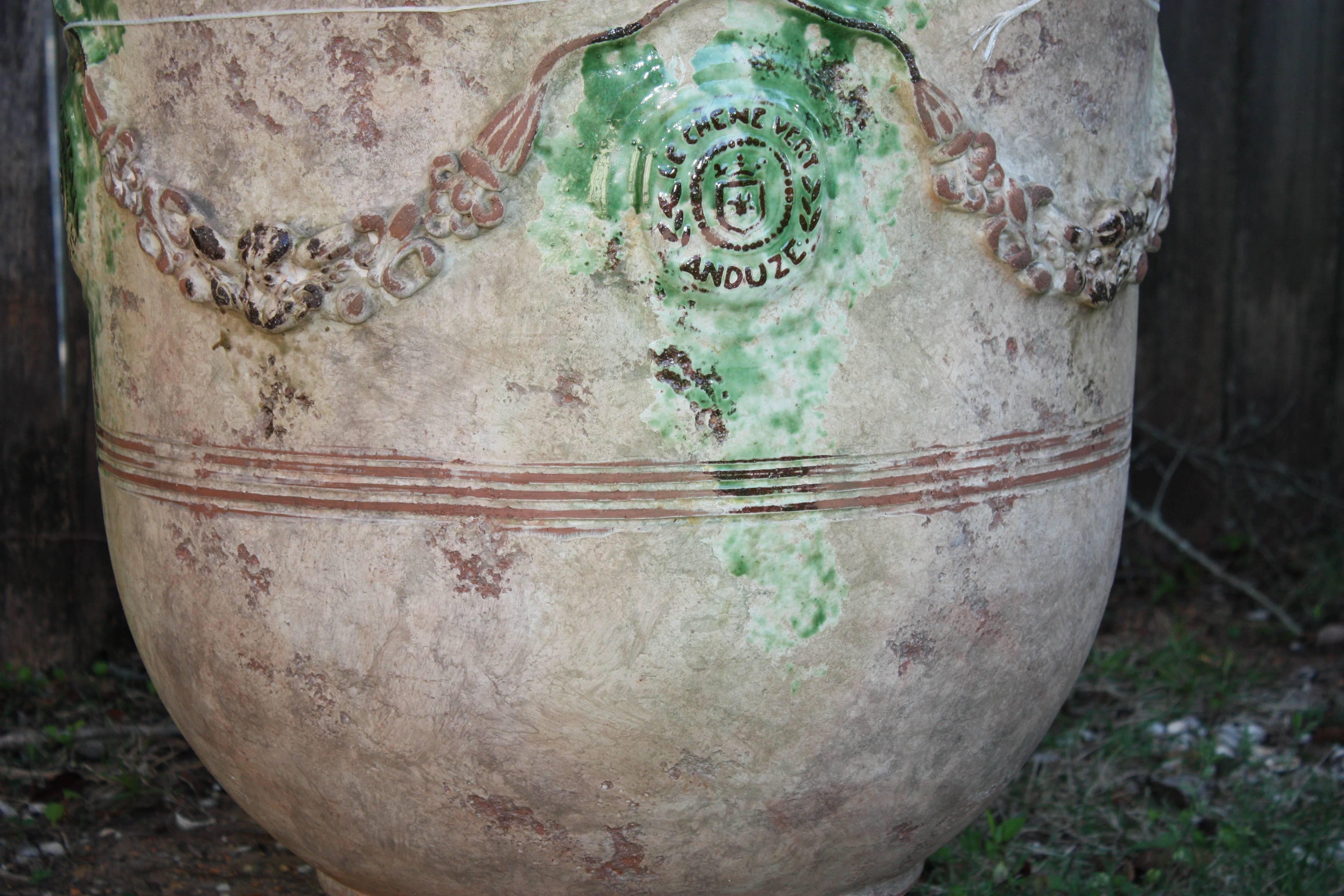 Large French anduze jar adorned by garlands. This jar sits upon a round pedestal base, and remnants of green glaze embellish its surface. We have several other sizes in stock.