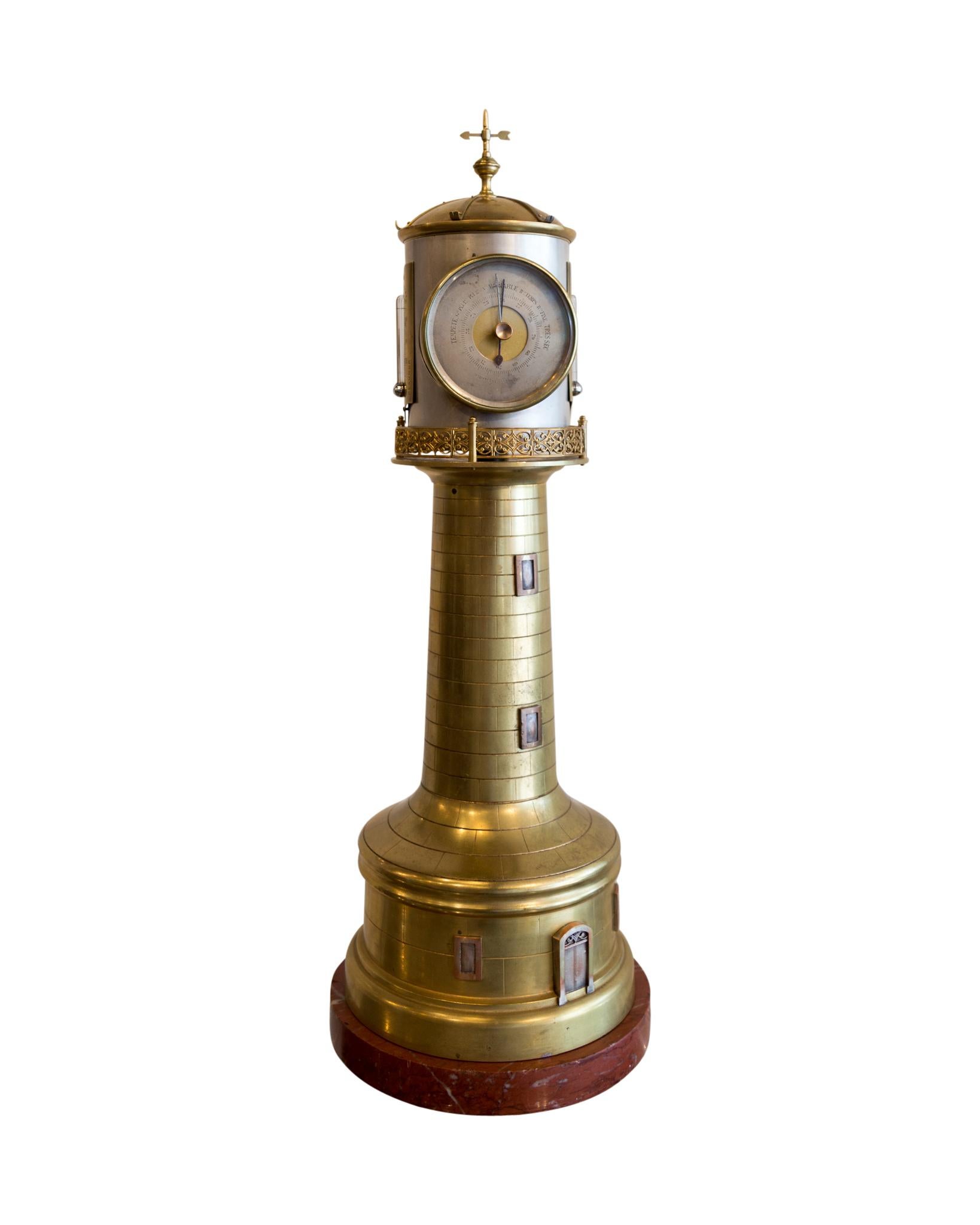 A particularly good example of a Guilmet lighthouse clock, circa 1880, resting on a circular rouge marble base. Above this is a two tier stepped base outlined to simulate stone blocks and there are windows and a door depicted on it. The mechanism