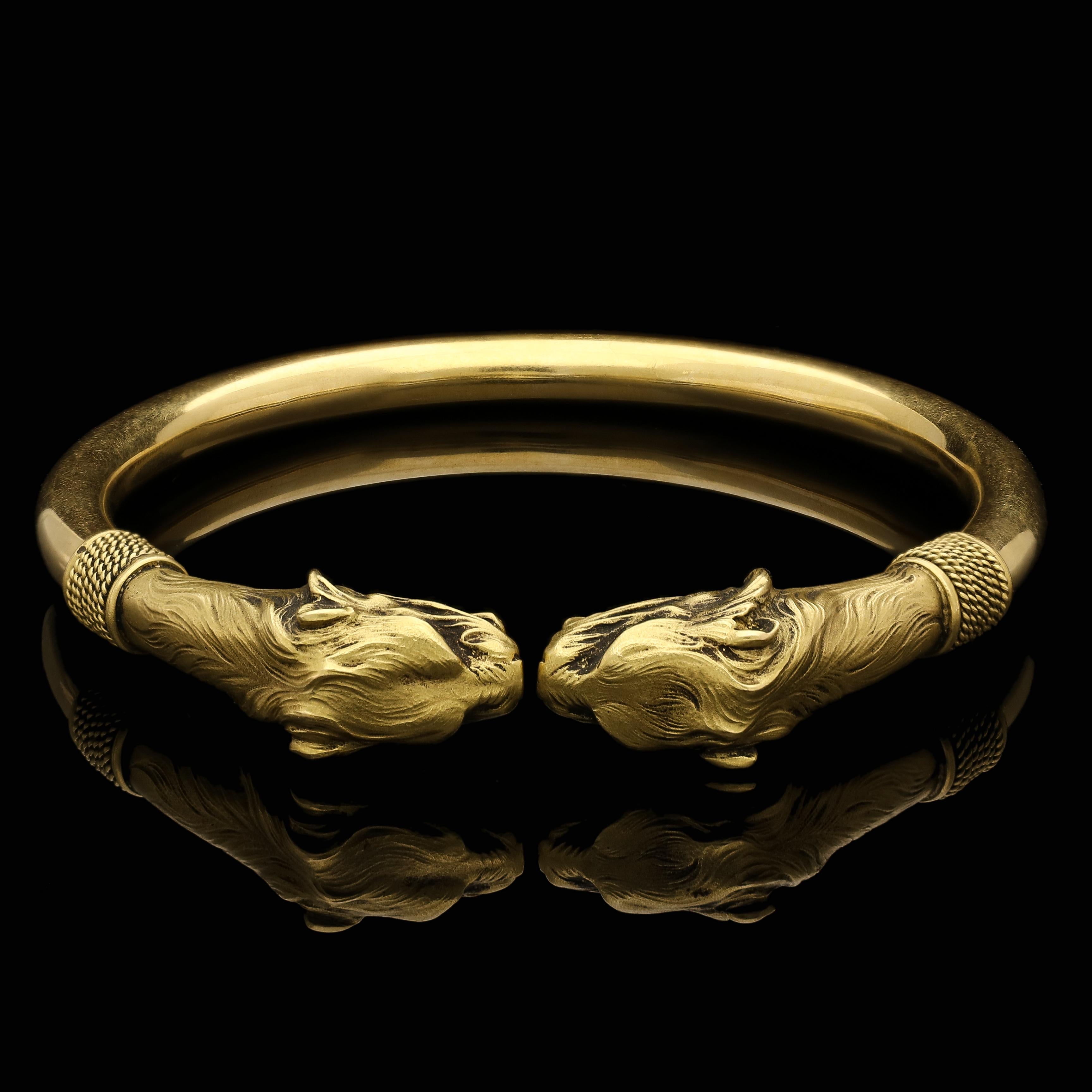 Description
An antique French gold lion head bangle c.1890s, designed as a solid bangle in 18ct yellow gold with rounded profile and small opening, each end terminated by a finely modelled lion head with open roaring mouth, sharp teeth, hooded eyes