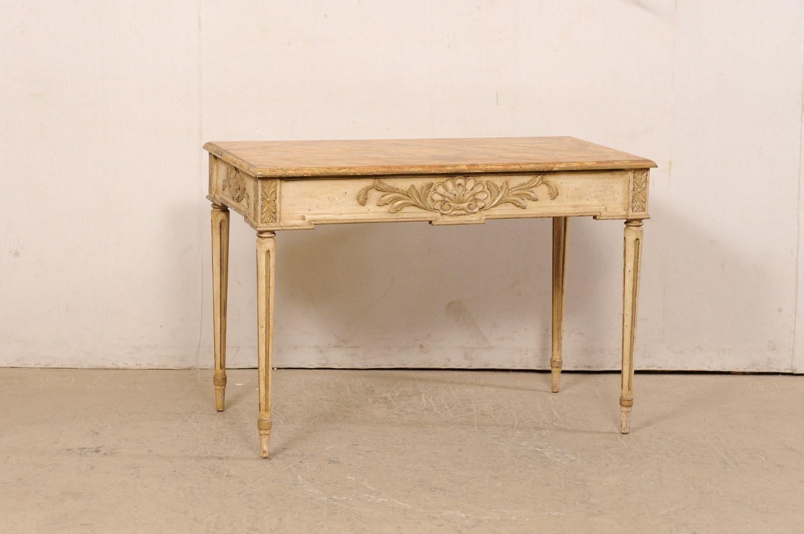 A French carved console table, with its original painted finish, from the early 20th century. This antique table from France has a rectangular-shaped top with hand-painted faux marble design, atop an apron which is embellished with carved shells