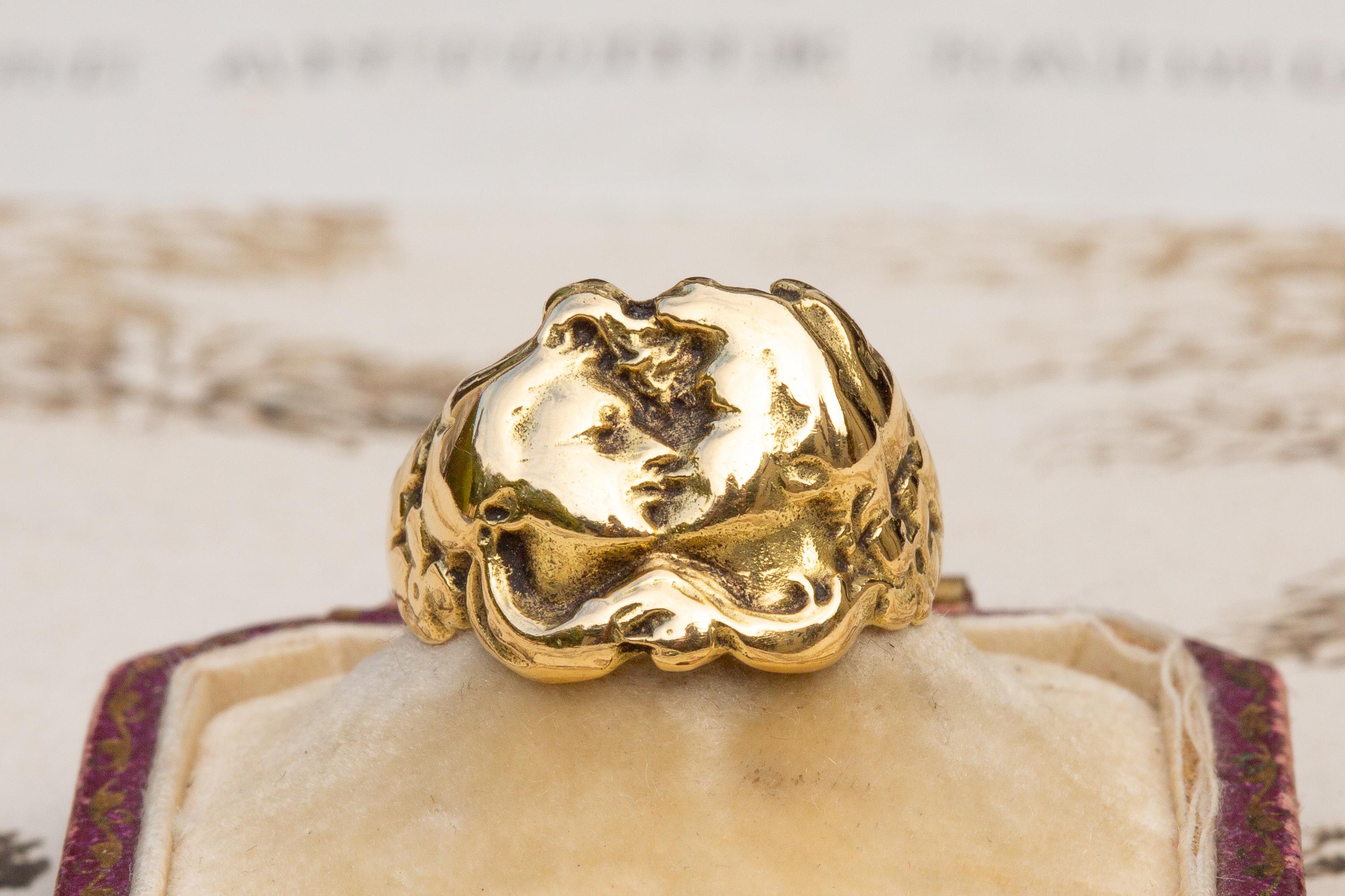 An iconic example of French Art Nouveau jewellery, this sculptural statement ring was made in Paris and dates to circa 1910. This unusual figural ring is crafted in 18K yellow gold and features two relief rendered faces pressed up against each other