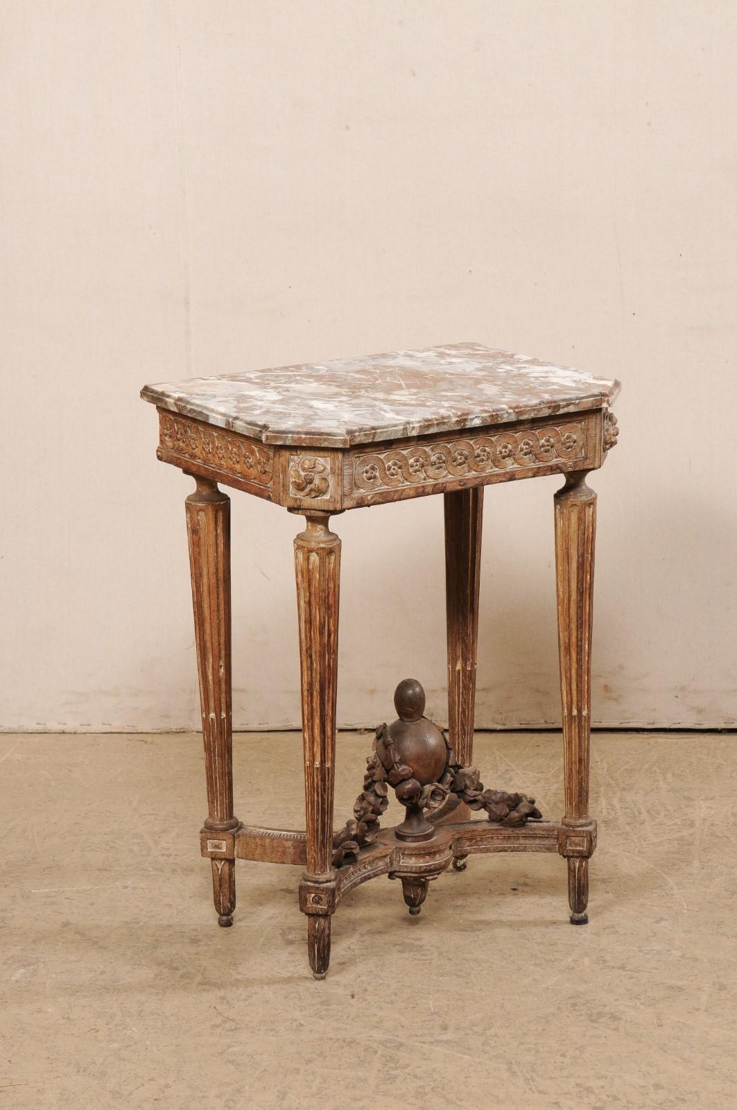Table d'appoint française de petite taille à plateau de marbre, avec un fleuron sculpté en forme d'urne sur le dessous, datant du tournant des XVIIIe et XIXe siècles. Cette table ancienne de France, qui a appartenu à Pamela Churchill Harriman