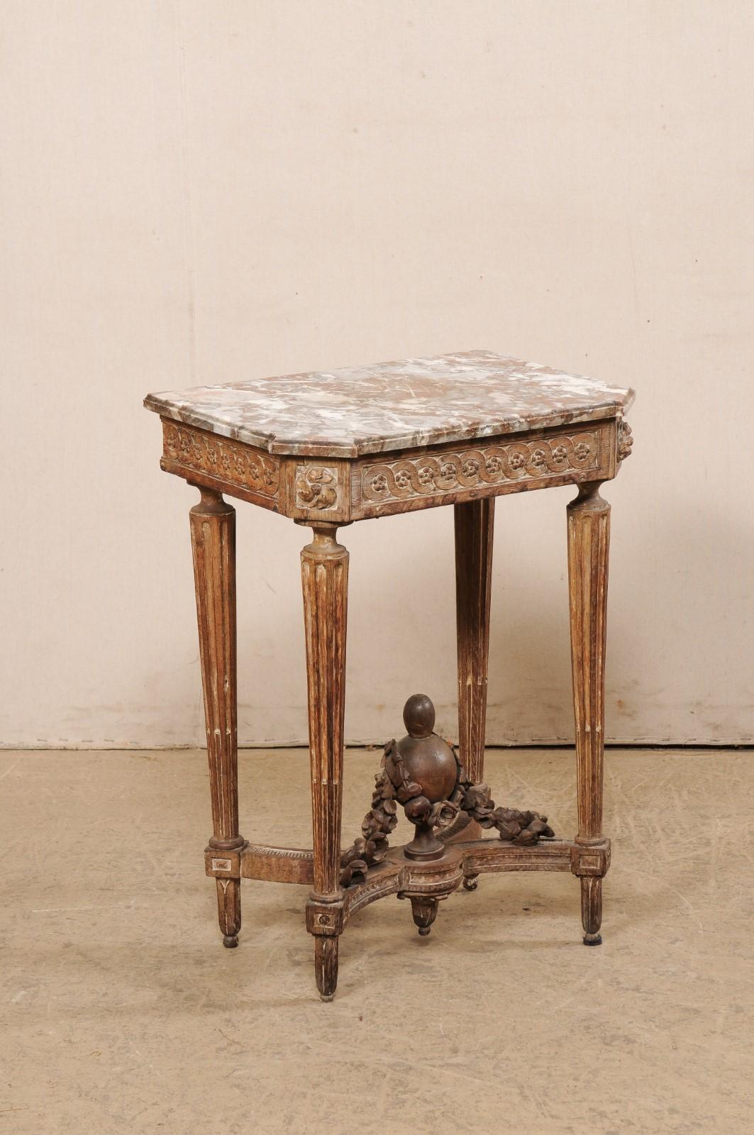 A French petite-sized marble top side table, with urn carved finial at underside, from the turn of the 18th and 19th century. This antique table from France, which once belonged to Pamela Churchill Harriman (former US Ambassador to France), is a