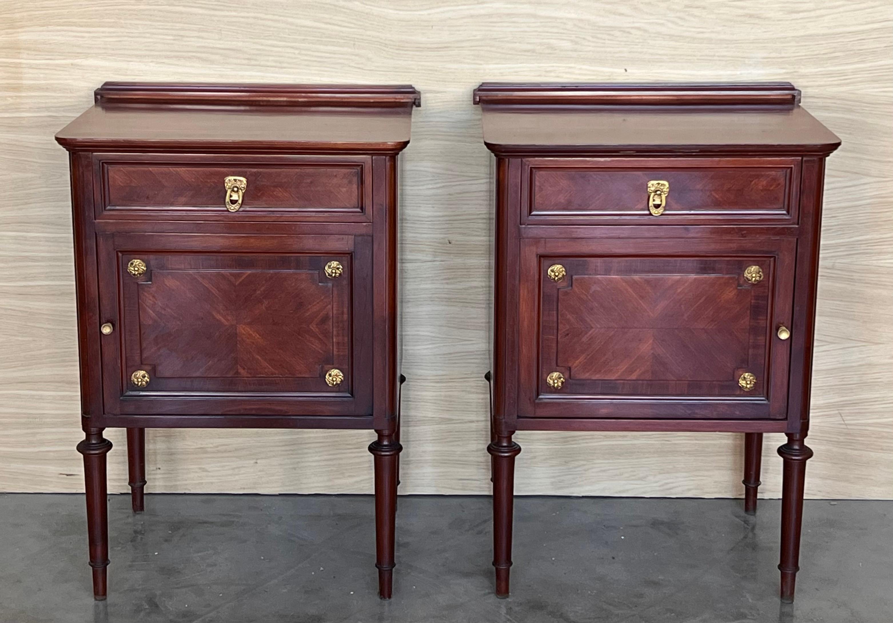 A 19th century French Louis XVI style mahogany side tables, or nightstands, with a fine crest that you can remove.  One dovetailed drawer above cabinet doors. Made of inlaid veneer of mainly mahogany. Slender legs. In excellent condition with only