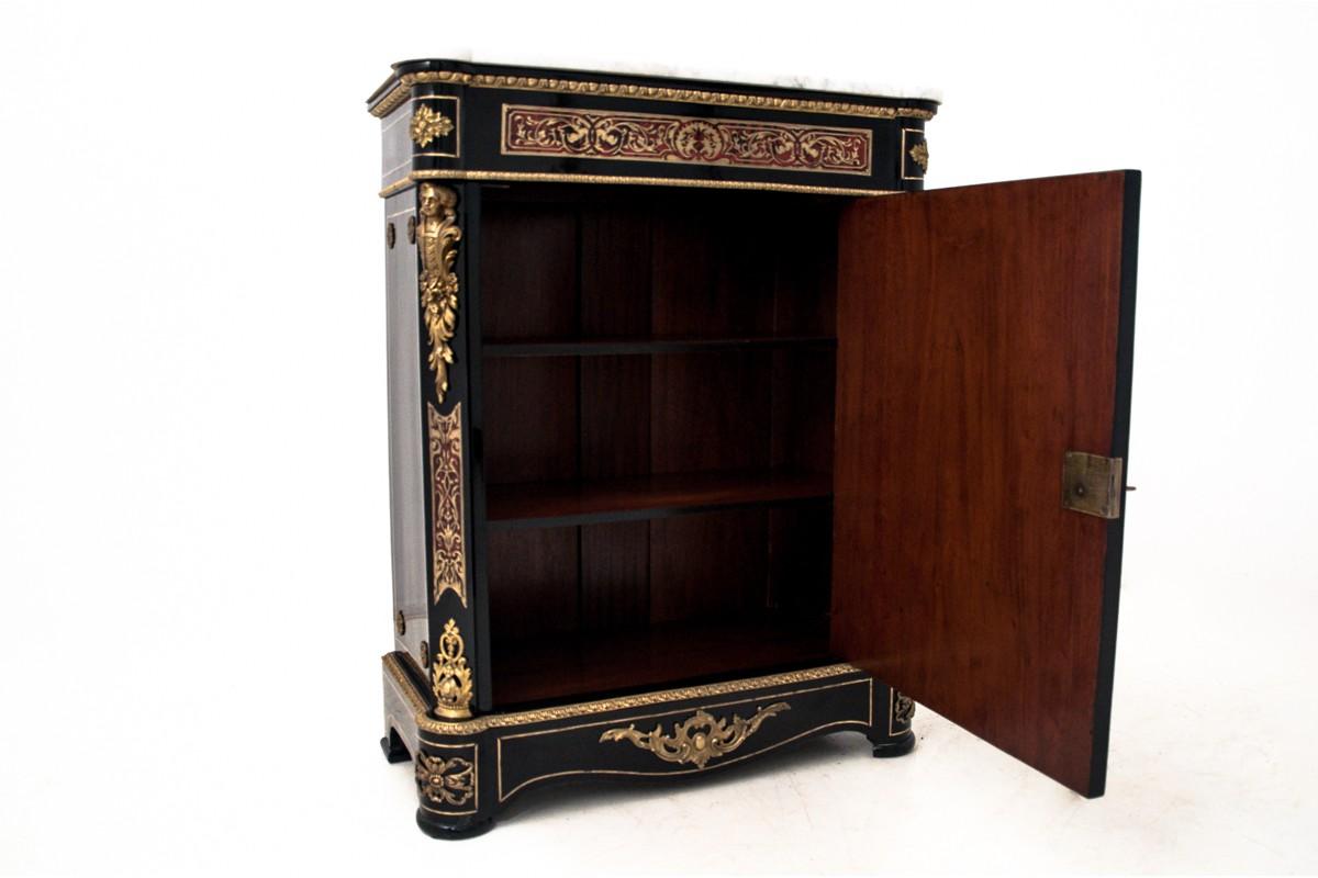 Cabinet manufactured in the 19th century, in France, modeled on the 17th century, baroque furniture of the French ebéniste, A. Ch. Boulle.
This piece of furniture is single-door cabinet with two shelves inside and marble top.
This commode