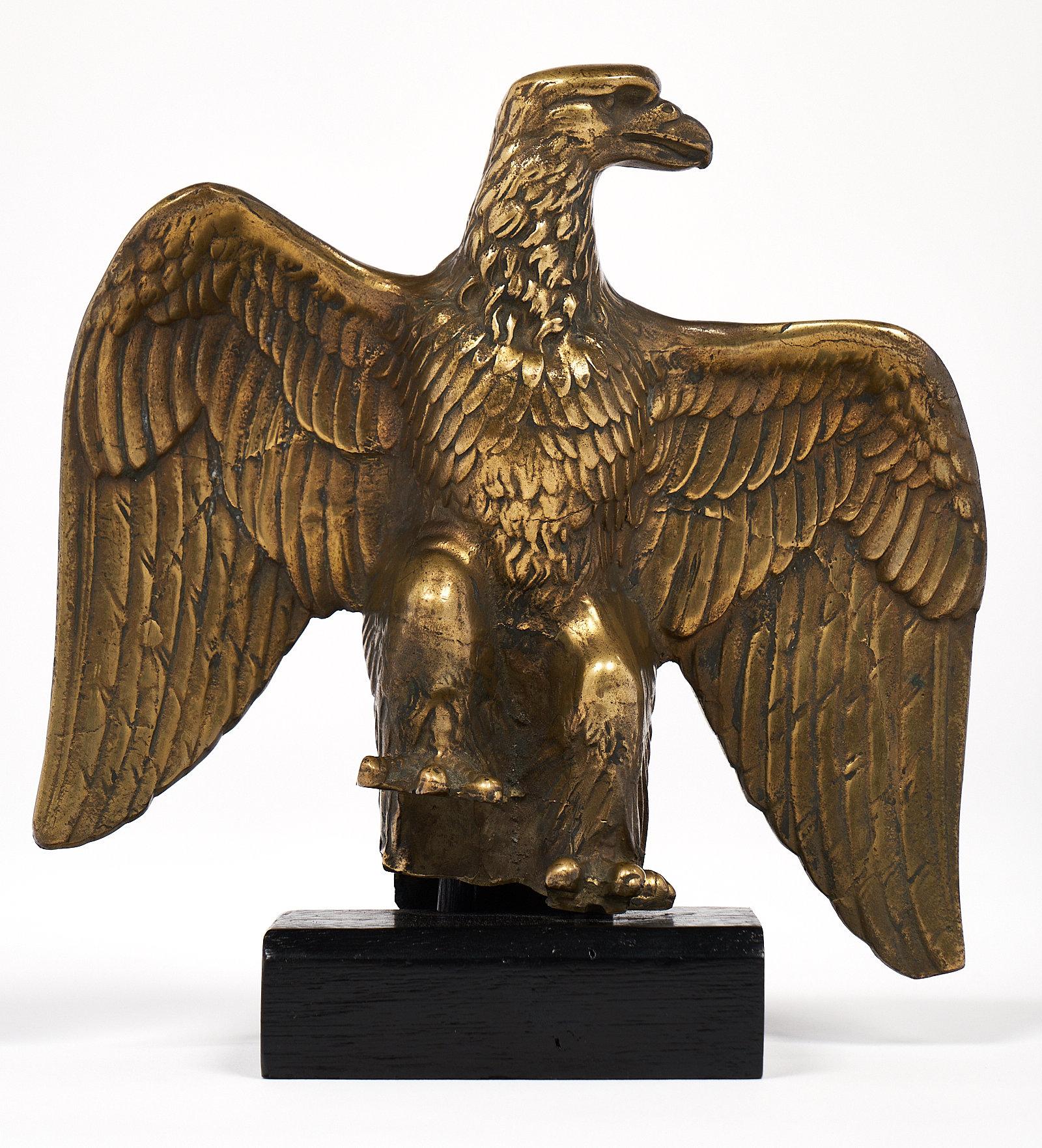 With extended wings, this intricately cast bronze eagle statue has a regal and powerful stance. The piece is supported by a wooden base, and the details on the wings and head on the statue have a beautiful patina from age. This antique decorative