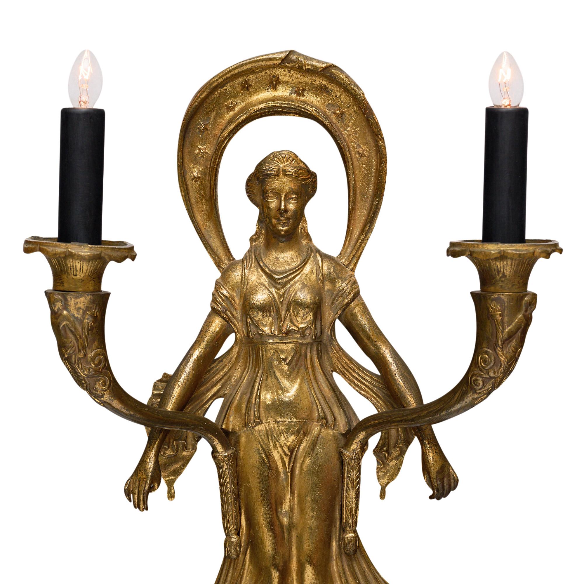 Sconces from France in the French Empire style in the manner of Pierre-Philippe Thomire. The pair is made of finely cast gilded bronze and features a female figure as an antique Greek Cariatide holding a pair of “Flambeaux” (torches). We loved the