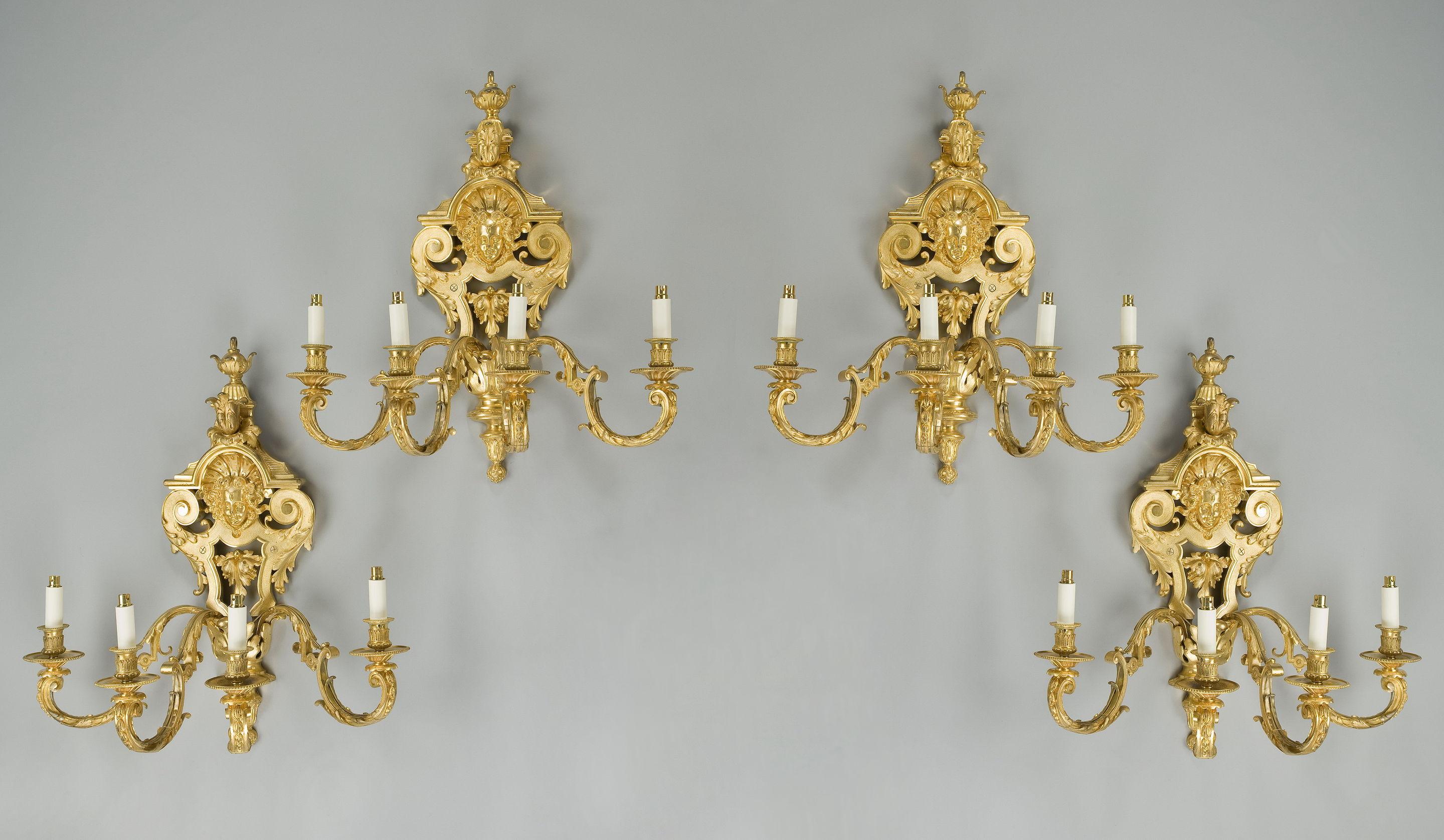 A set, each of these four fine French gilt wall lights includes a strapwork cartouche centred on a female mask below a leaf and urn finial and four supporting c-scroll brackets. Signed ‘Rode a Paris’. Circa 1890.
 
