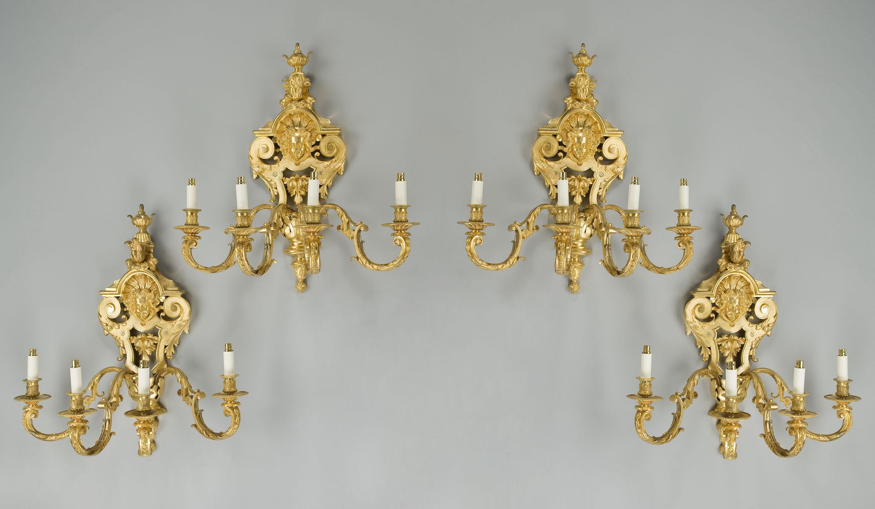 Un ensemble, chacune de ces quatre fines appliques murales françaises en vermeil comprend un cartouche à entrelacs centré sur un masque féminin sous un fleuron en forme de feuille et d'urne et quatre supports en forme de rouleau. Signé 
