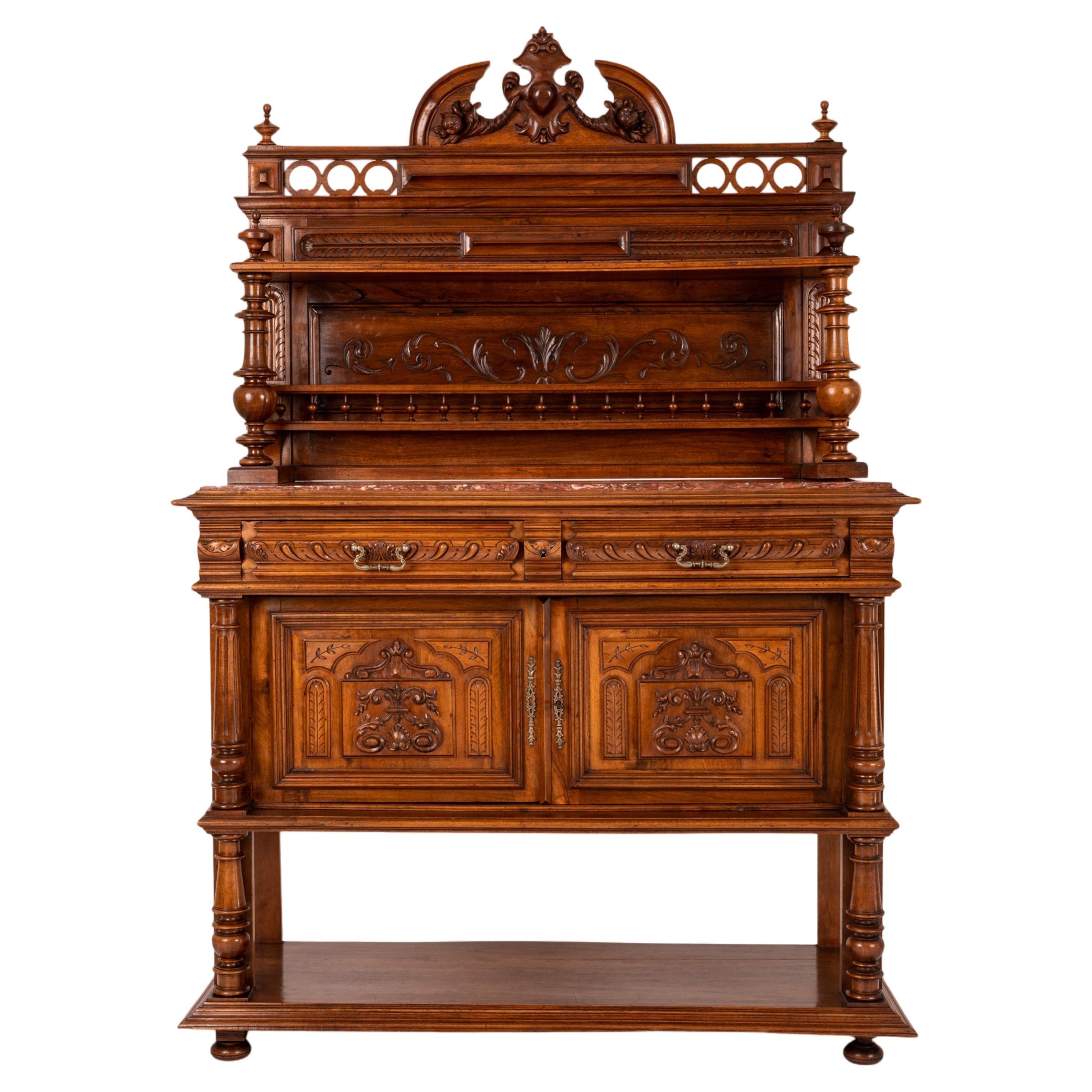 A very good antique French carved walnut dessert server, buffet, liquor cabinet in the Renaissance Revival taste, circa 1880.
The carved back with a crest of twin cornucopia and a carved Fleur-de-Lis, flanked by two pairs of turned finials with a
