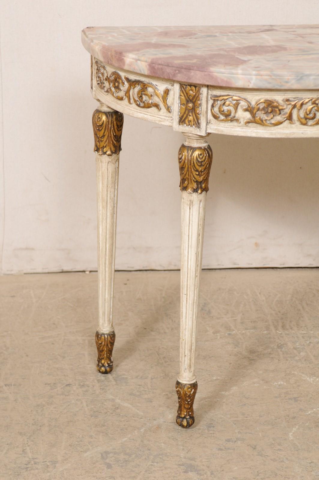 A French demi-lune console table with its original marble top from the early 20th century. This antique table from France is half-moon shaped with beautifully colored marble, which rests atop an exquisitely carved decor of leaves and flowers on its