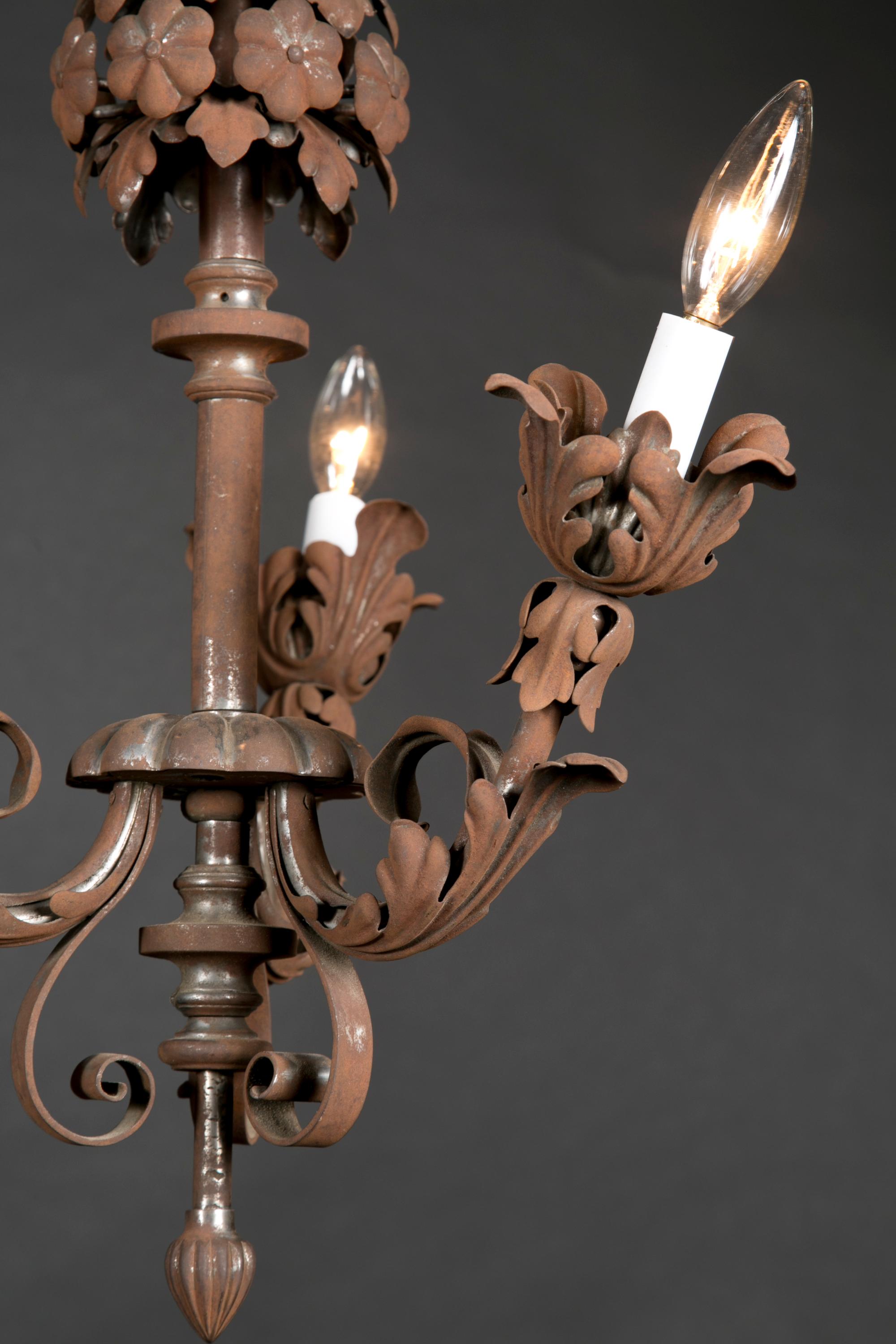 This French cast iron chandelier features beautiful foliate arms & a fantastic floral decoration at top. Notice, from the top, the acanthus leaves and rosettes grouped in a sphere, moving down the stem and along the three arms we find more acanthus