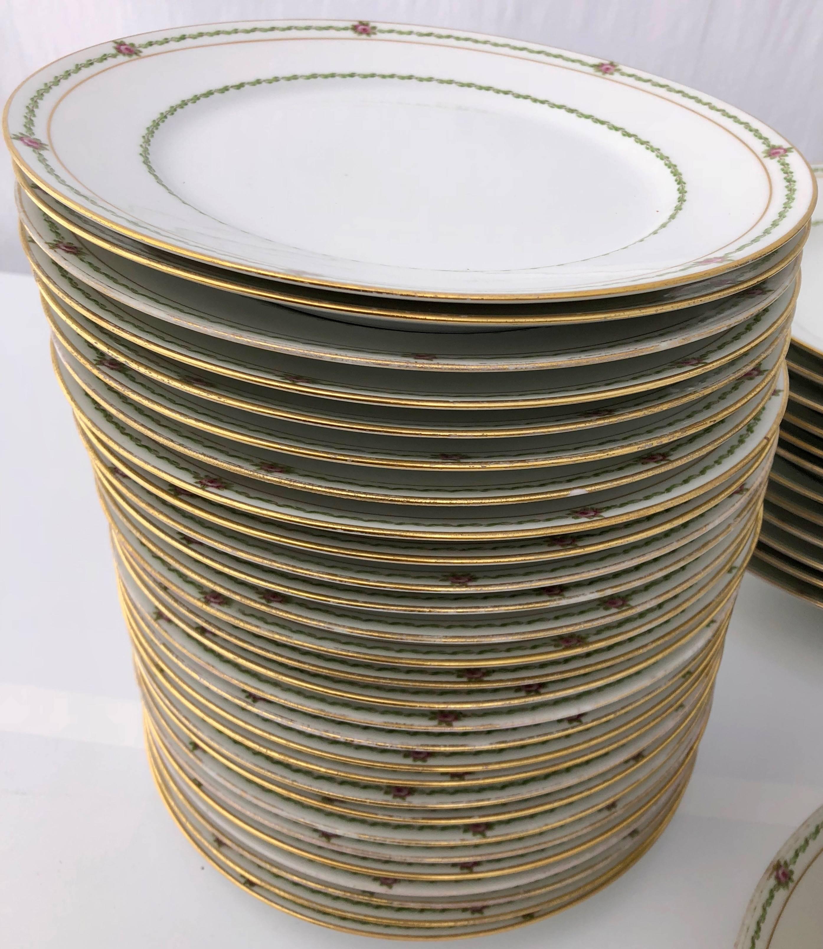 This beautiful set of French porcelain china plates has a delicate rose pattern and a gold plated border. It is an extensive setting totaling 94 pieces. This model has been in the same family in Lorraine for at least 80 years so it could be dated