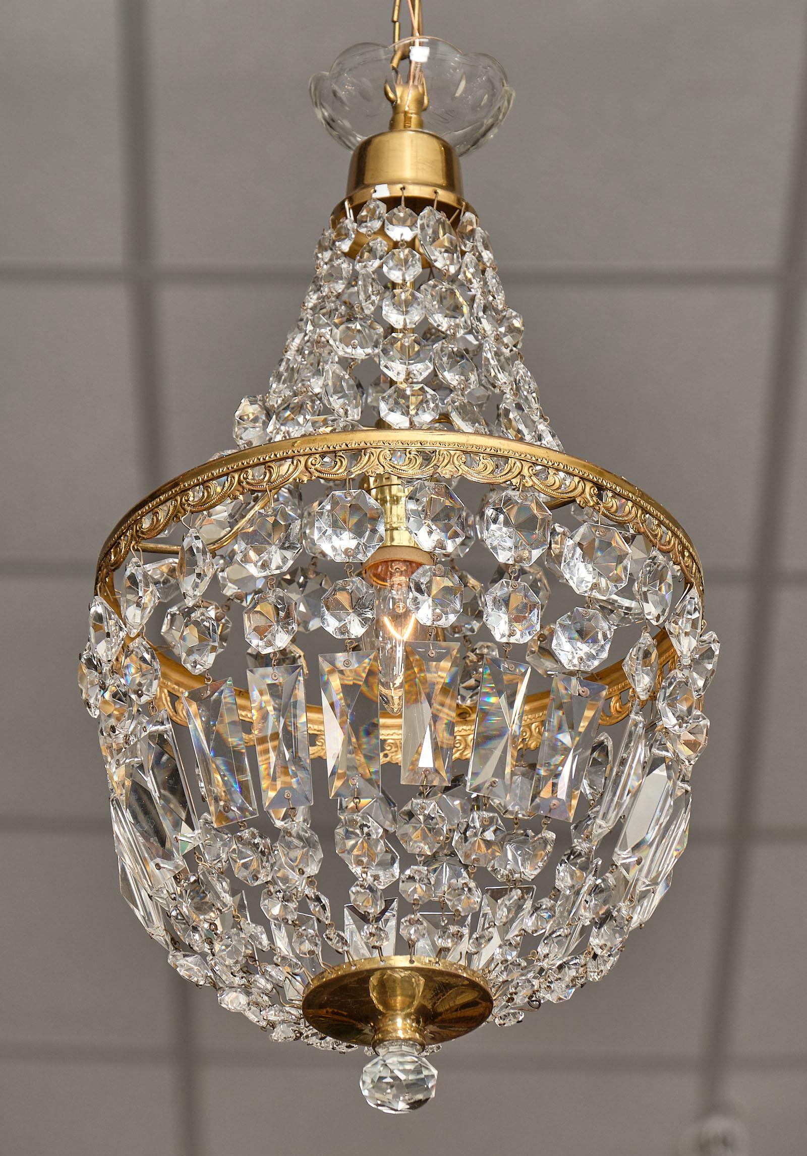Pair of French antique crystal pendant chandeliers in the Empire style. Each fixture features an array of cut crystal connected with an embossed gilt brass crown. They have been newly wired to fit US standards. The current height from ceiling is 31