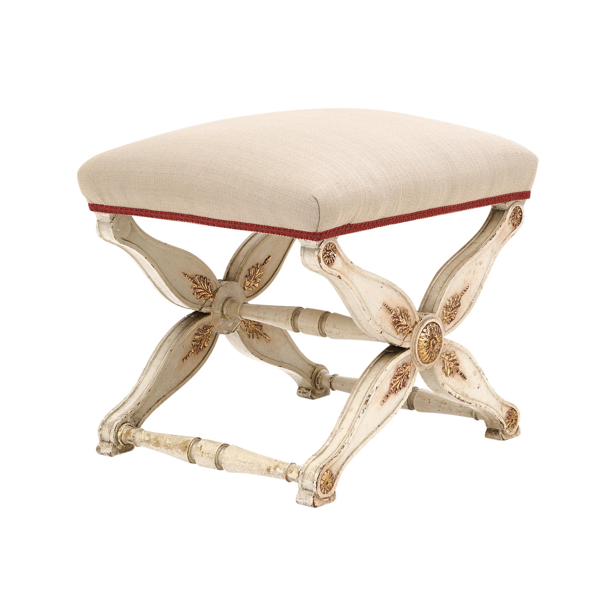 Curule stool, French, made of hand-carved and hand-painted beech wood in a beautiful Trianon gray color. There are gold leaf accents throughout. Newly upholstered in a linen blend.