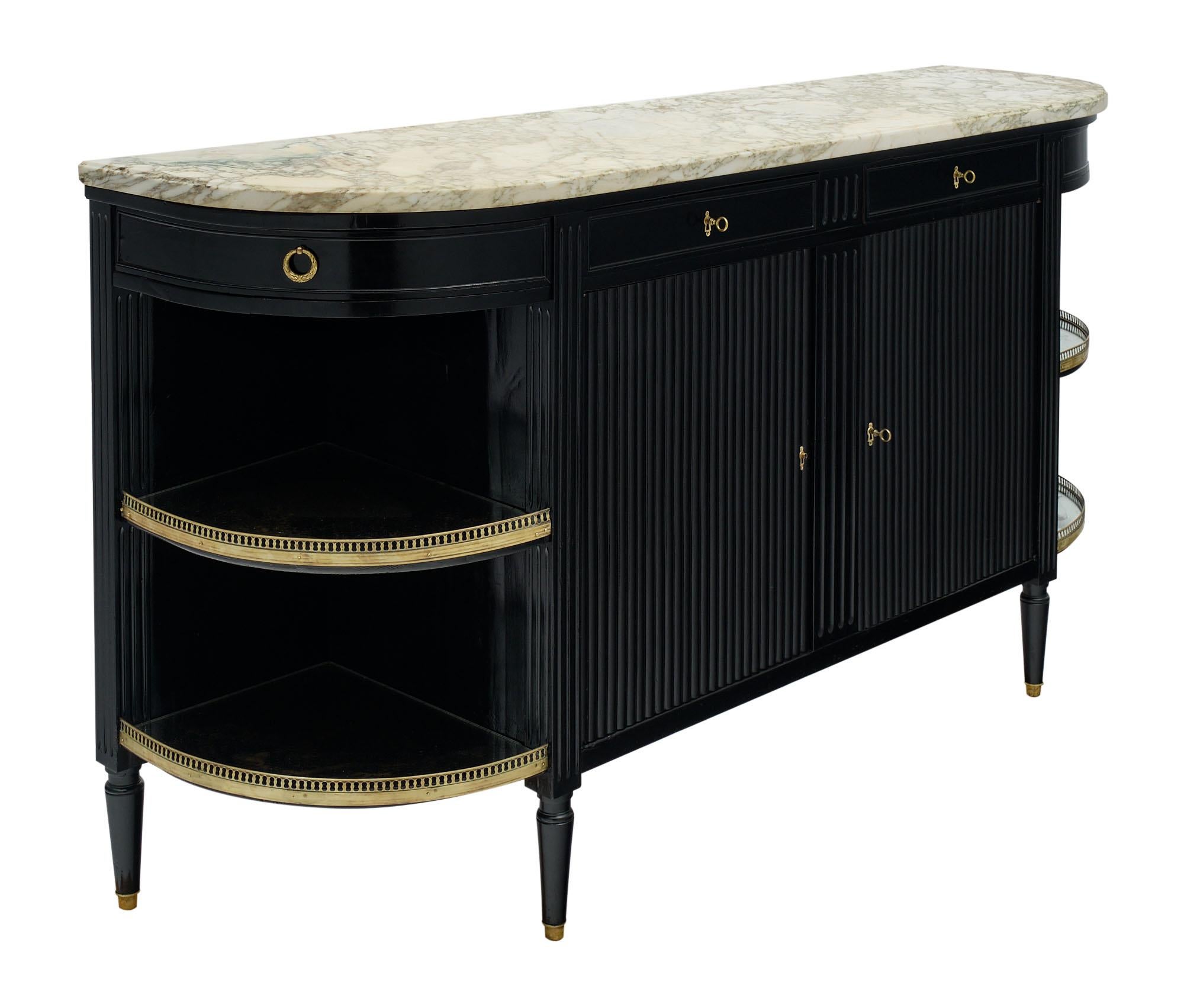 Buffet /enfilade in the French Louis XVI style made of mahogany that has been ebonized with a museum-quality French polish for luster. An intact Carrara marble top is original to the piece. Open corner shelving is veneered with antiqued mirror. Four