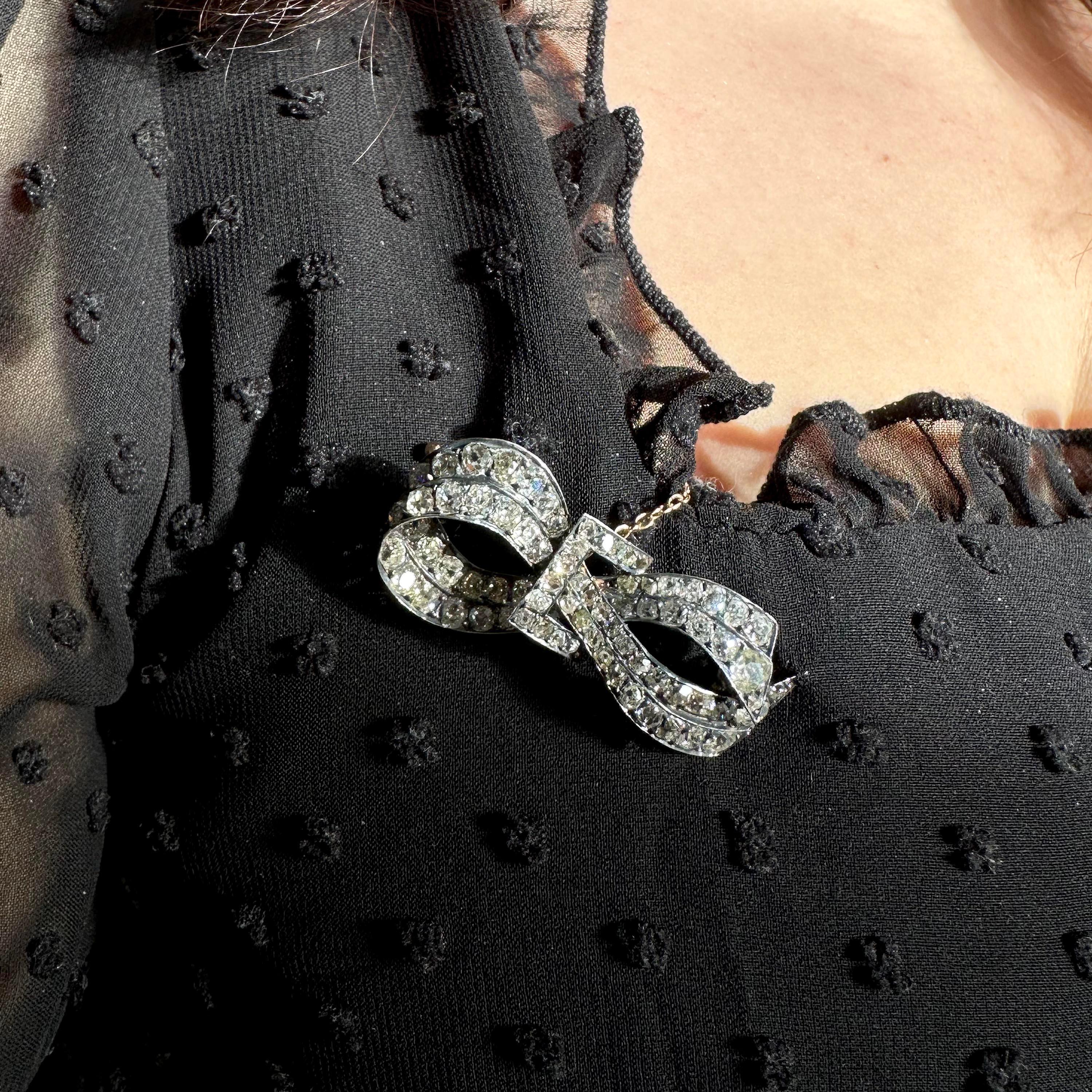A French antique diamond and silver-upon-gold bow brooch, set with two rows of old mine cut diamonds, with a total weight of approximately 6.00 carats, in silver grain settings, backed in gold, forming a ribbon loop, clasped by a rectangular buckle,