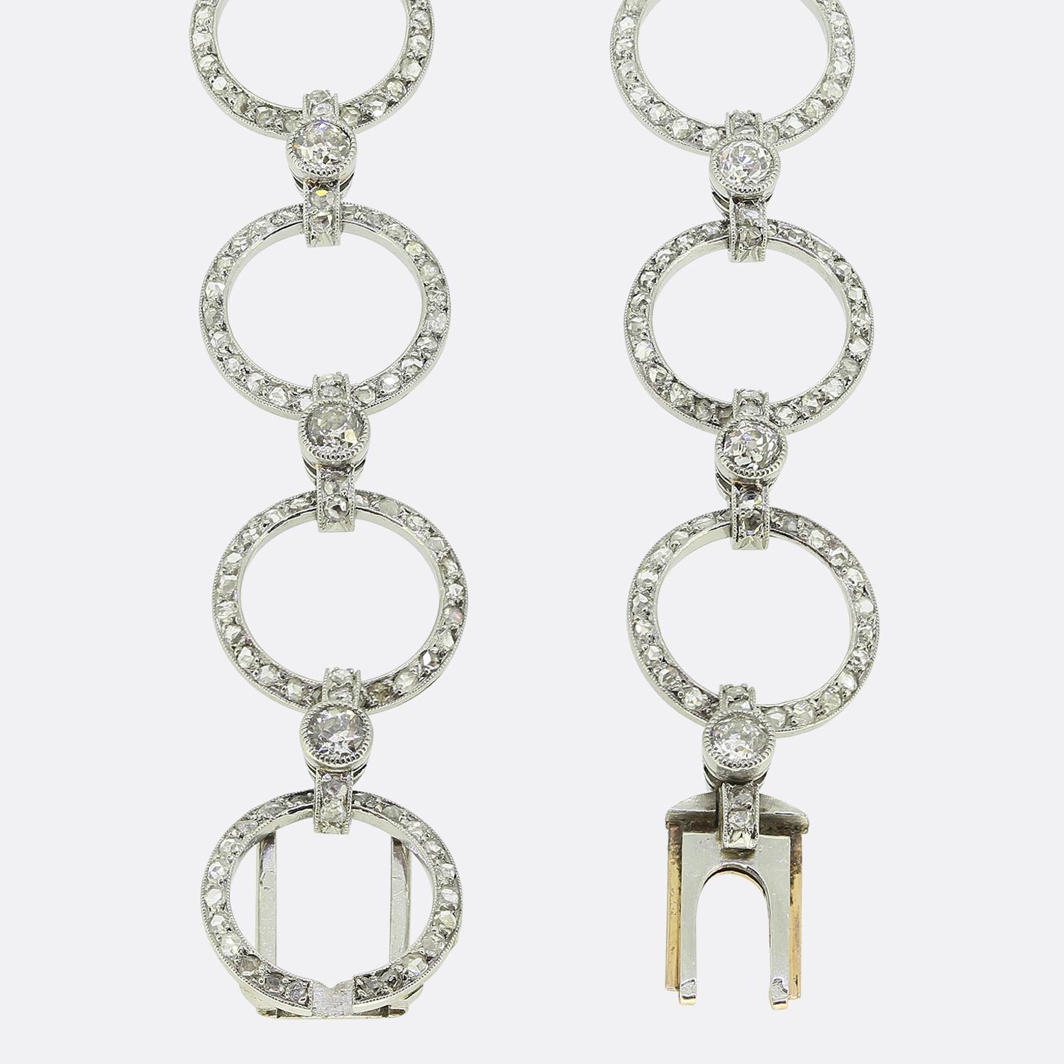 Here we have a stunning bracelet featuring a series of interlinked circles, each adorned with shimmering rose cut diamonds. Predominantly crafted from platinum, this antique piece showcases a harmonious articulated design with round faceted old mine
