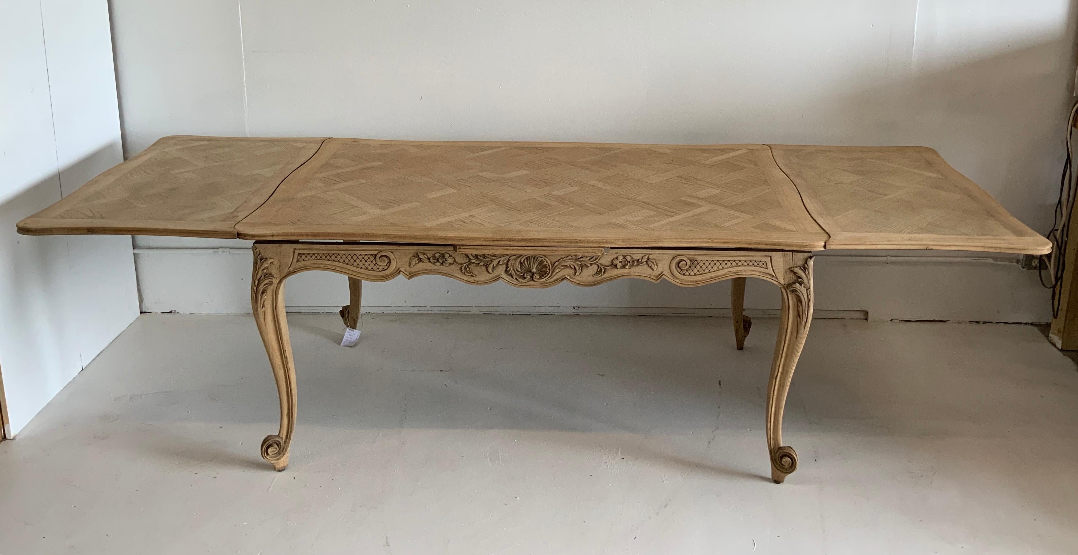French antique dining table Louis XV style, with a parquet top. The bleached finish has been done by us. This piece comes from the South of France in 1950.
The 2 slide out leaves are 23