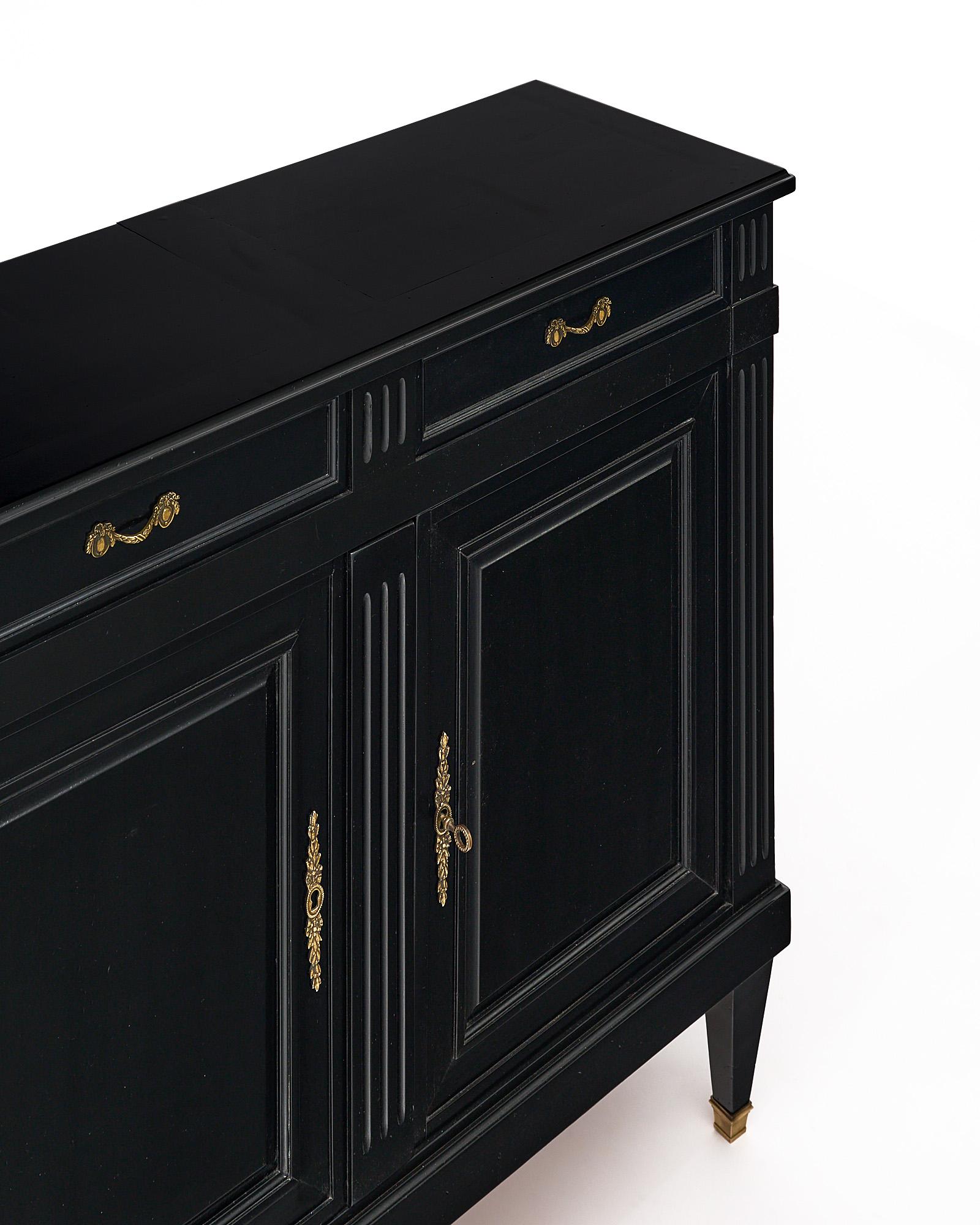 Buffet; French; finished in an ebonized French polish for a museum-quality luster. This Directoire style piece has two dovetailed drawers over two doors which open to an interior shelf. The hardware is all original and made of brass.