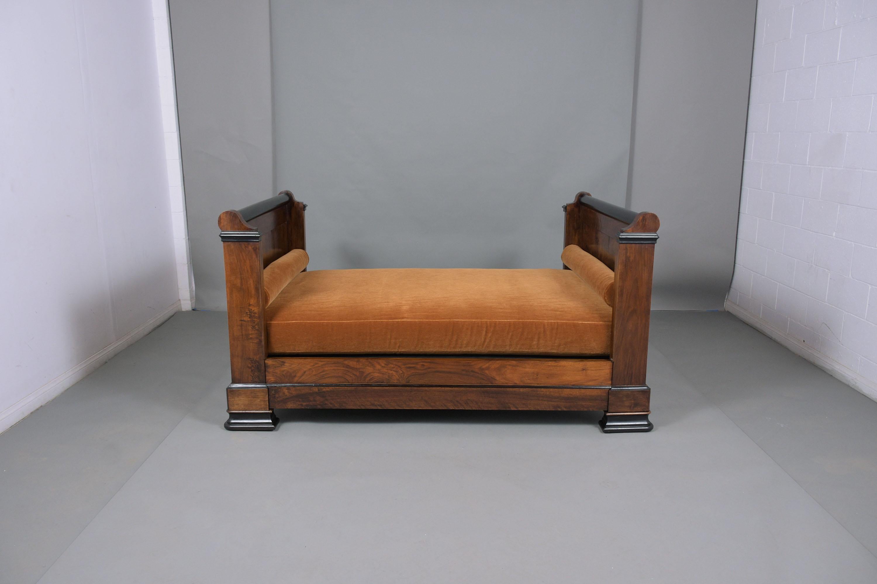 An extraordinary late 19th-century Empire daybed handcrafted out of walnut wood and been professionally restored by our craftsmen team in-house. This elegant daybed features a straight headboard, and molding details the bed is stained with a walnut