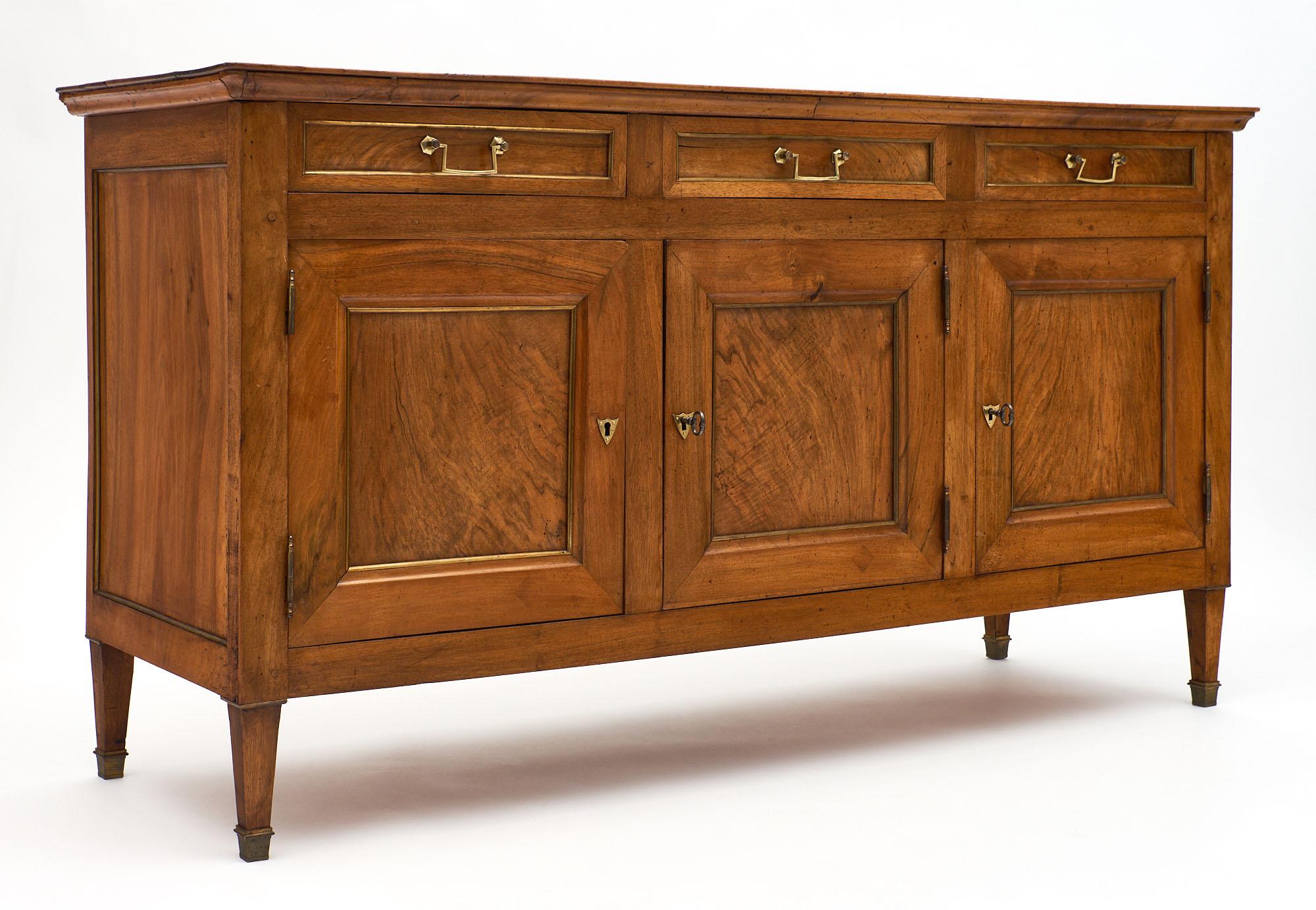 A fine early 19th century Directoire period French antique buffet made of blonde walnut and featuring three dovetailed drawers, three doors with all original bronze hardware. We loved the fact that everything is original on the piece, with very