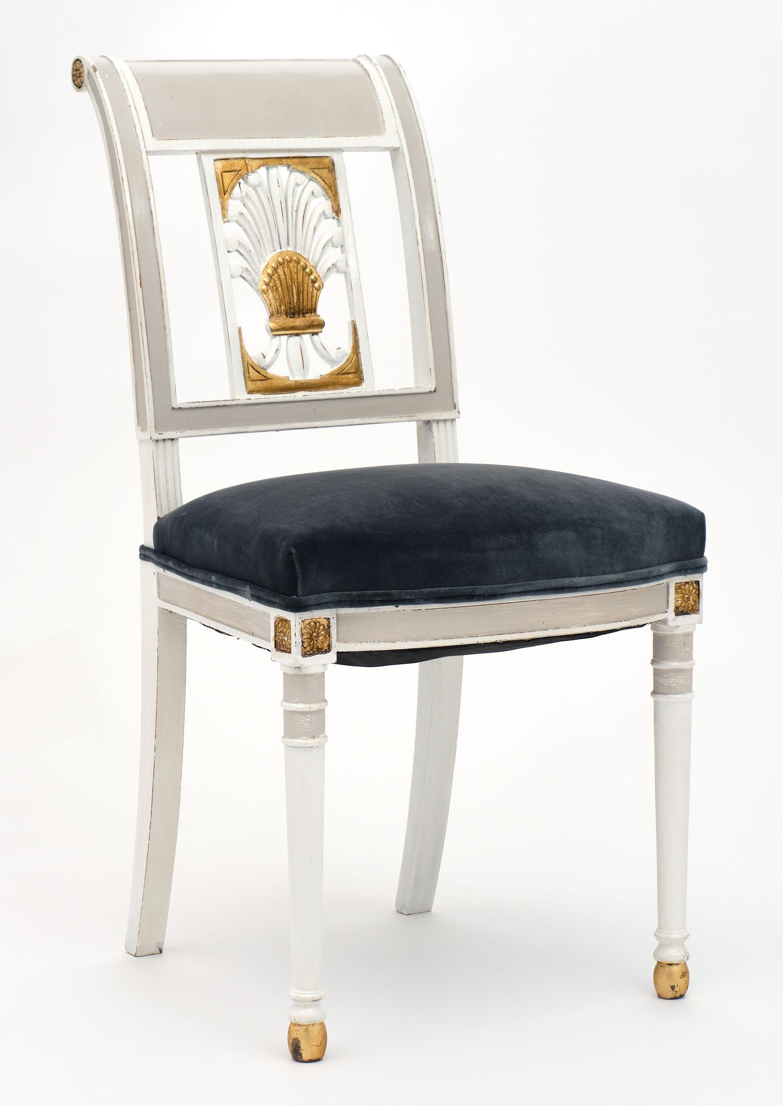 Directoire style antique painted French chairs in a “Trianon” gray color with white and gold leaf detailing. We love the elegant stylized acanthus leaf details on the backs and the tapered front legs with saber back legs. They have been newly
