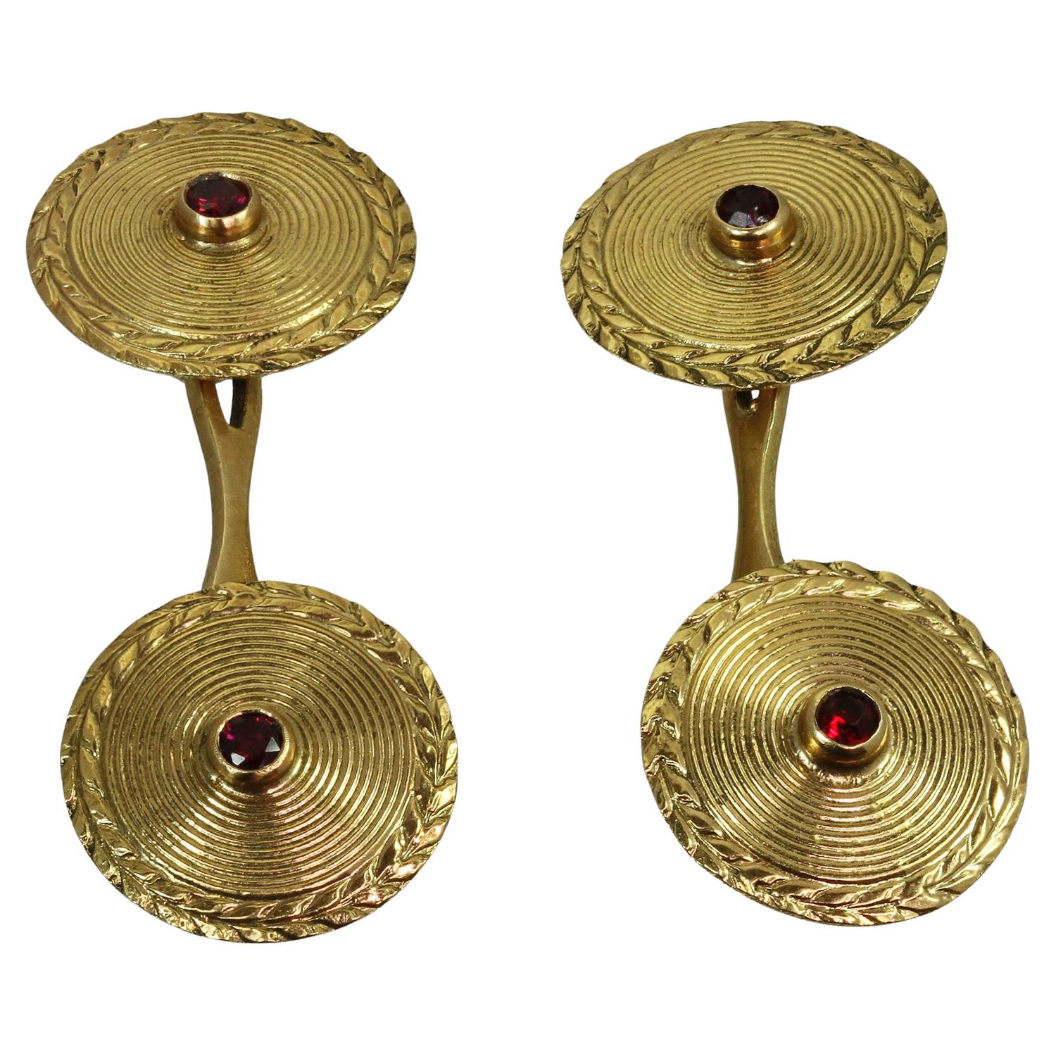 Ces boutons de manchette ronds, rares et anciens, sont ornés d'un motif décoratif double face en or jaune 18 carats, rehaussé de rubis rouges ronds. Fabriqué en France dans les années 1930. Dimensions : 0,55