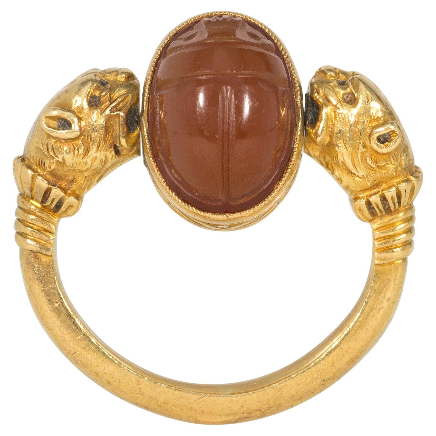 A Victorian Egyptian Revival carnelian and gold swivel ring centered by a carved carnelian scarab set in a foliate-carved gold surround, flanked by gold lion heads, in 18k.  France.

Face-up dimensions approximately 7/16