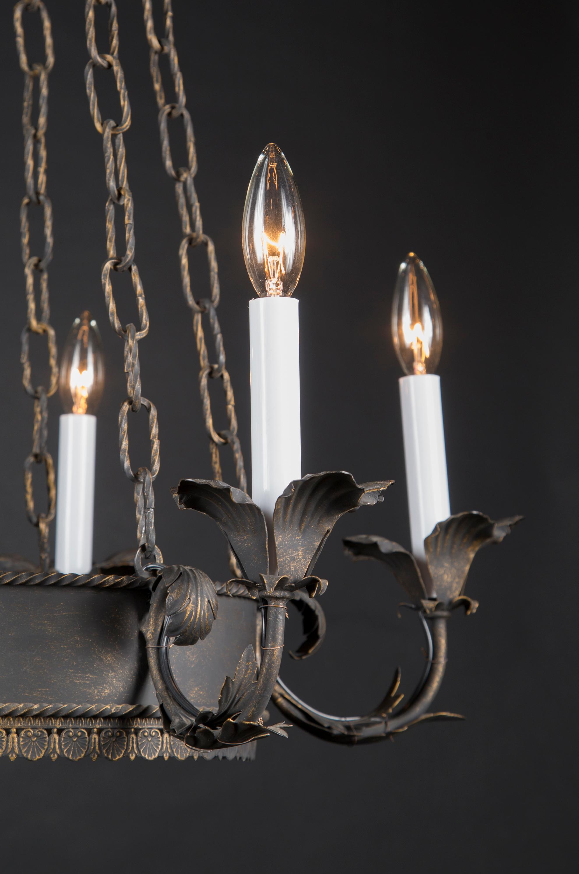This French Empire tole and iron chandelier is painted black with a beautiful patina. The piece dates back to the late 19th century and offers a combination of simplicity and details; note the five strands of spiraling chain that are mirrored in the