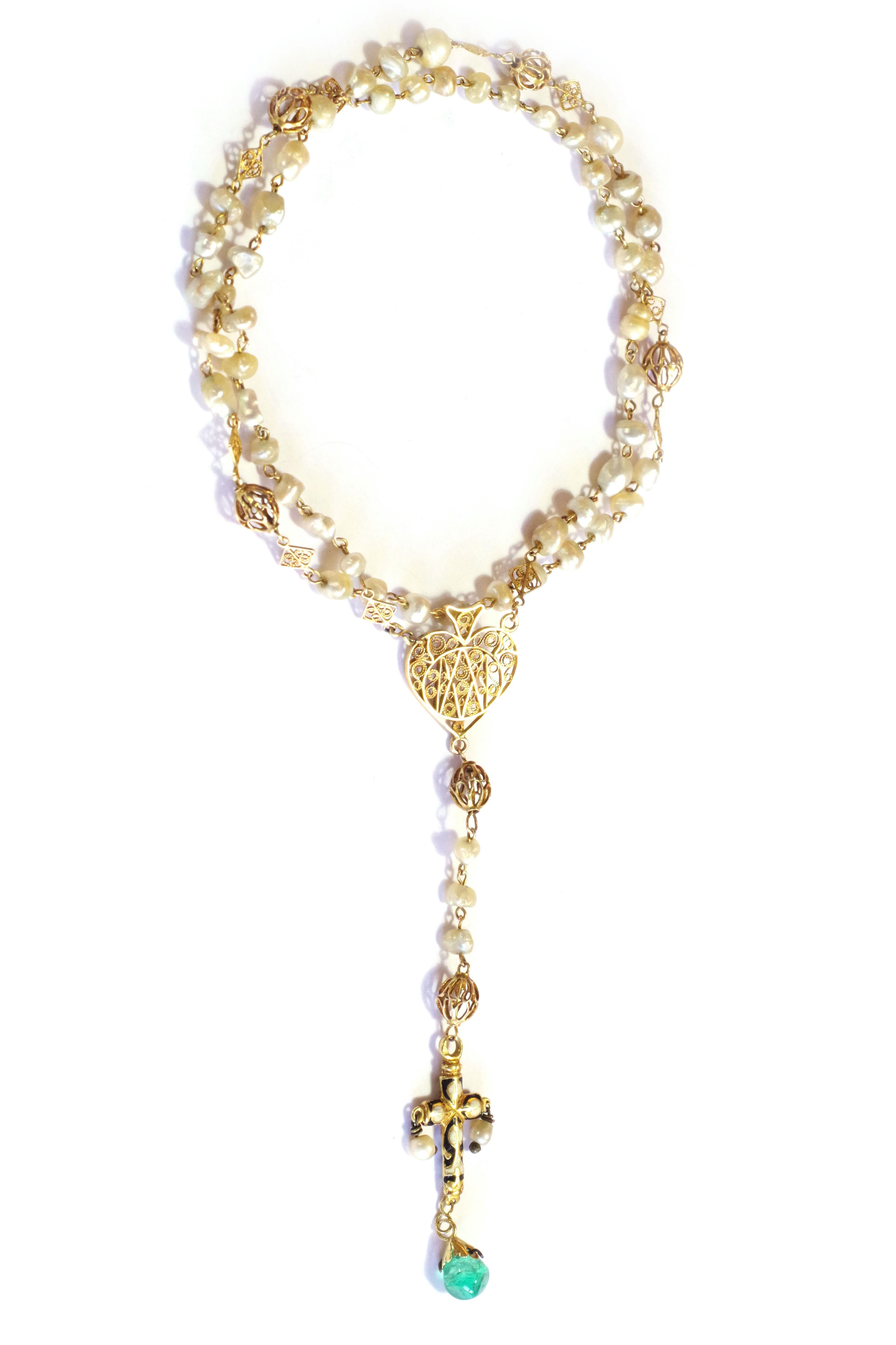 Enamelled gold emerald rosary in 18 karat yellow gold. The rosary is in yellow gold with natural baroque pearls alternating with an openwork spherical element and filigree motifs. The cross is black and white enamelled and enriched with two pendant