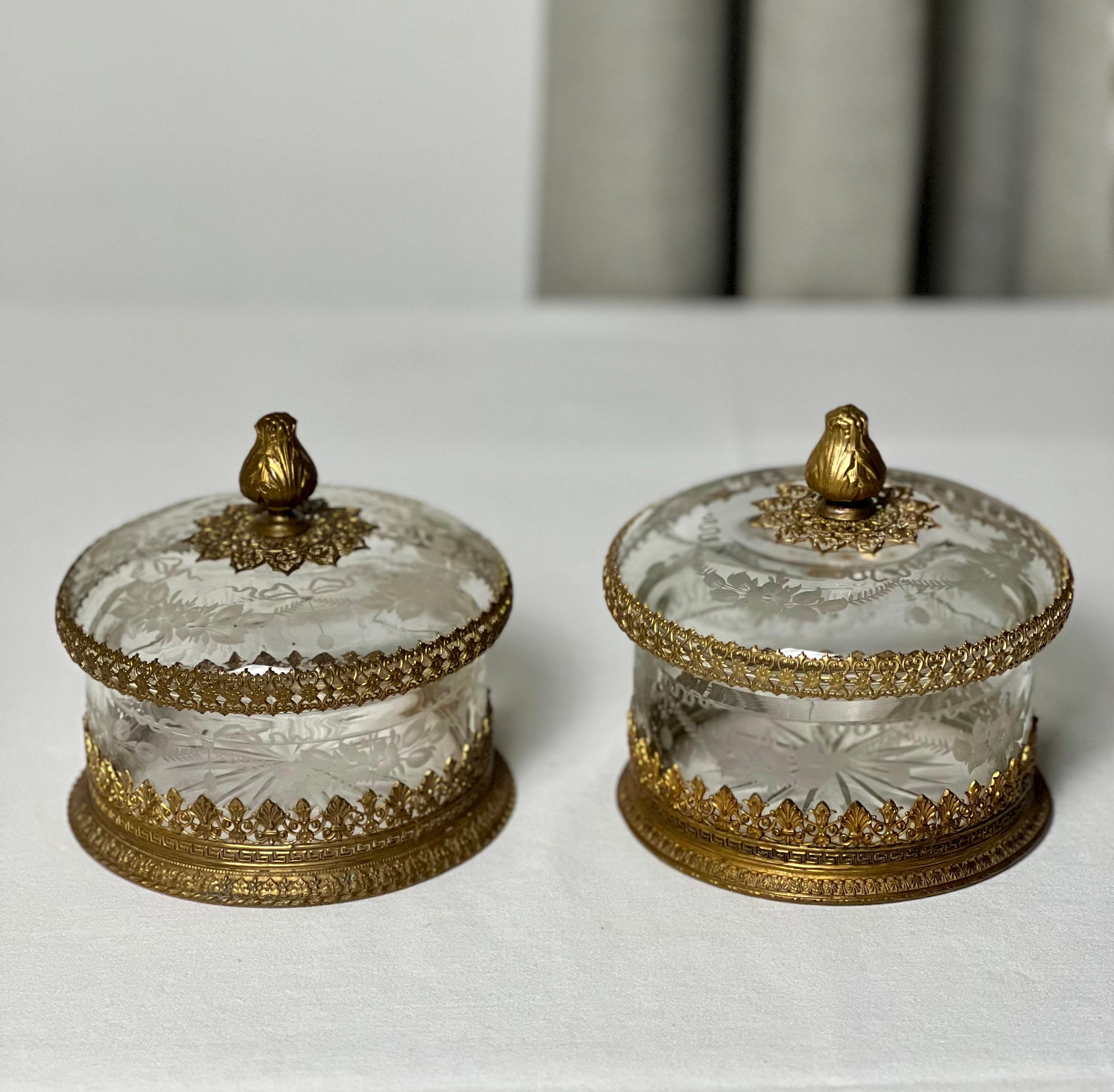Pair of French antique etched and faceted cut crystal lidded boxes with ormolu mounts, c. early 20th century.

Gorgeous gilt bronze mounted boxes with intricately etched crystal of flowing floral swag and bow detail with a faceted cut starburst