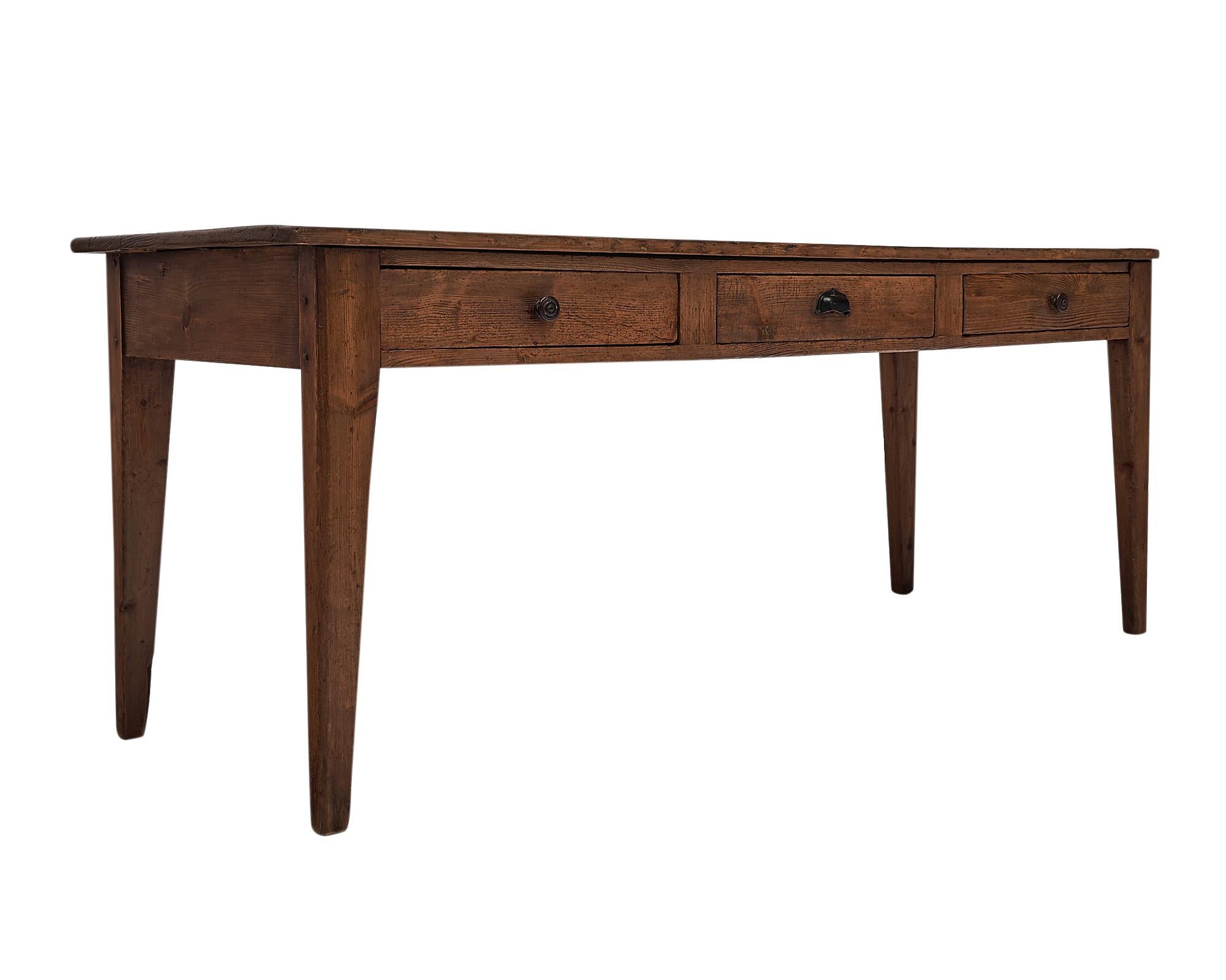 Farm table, French, from the Rhone Valley. This piece is made of fir and has strong tapered legs. The planked top is supported by a base with three dovetailed drawers down one side, as was customary on these functional farm tables. It has a lovely