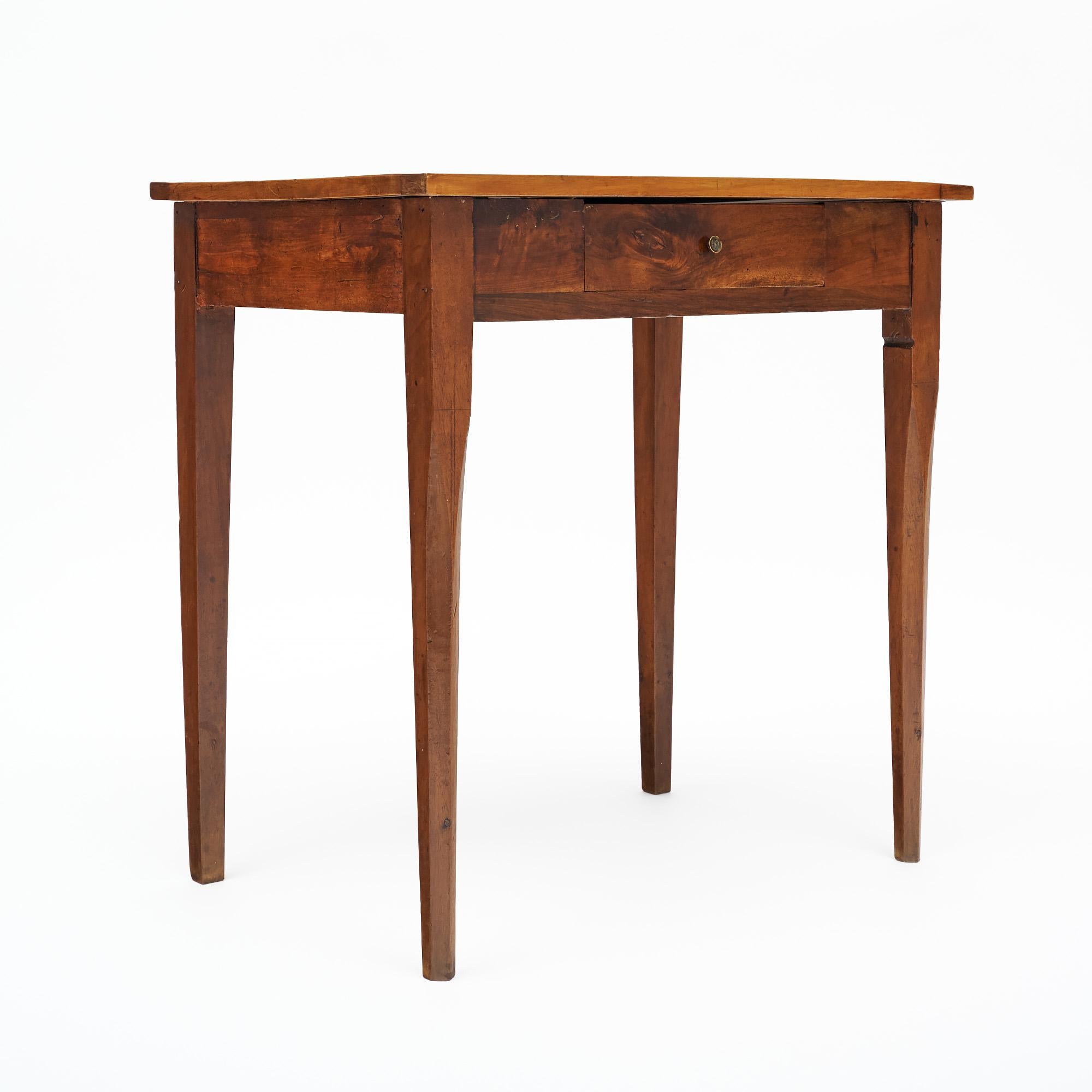 Writing table from France made of solid wood construction, primarily cherry wood and walnut. It has been finished with a bees wax. There is a single dovetailed drawer on the front side with a small original brass pull. An inlaid wood border around